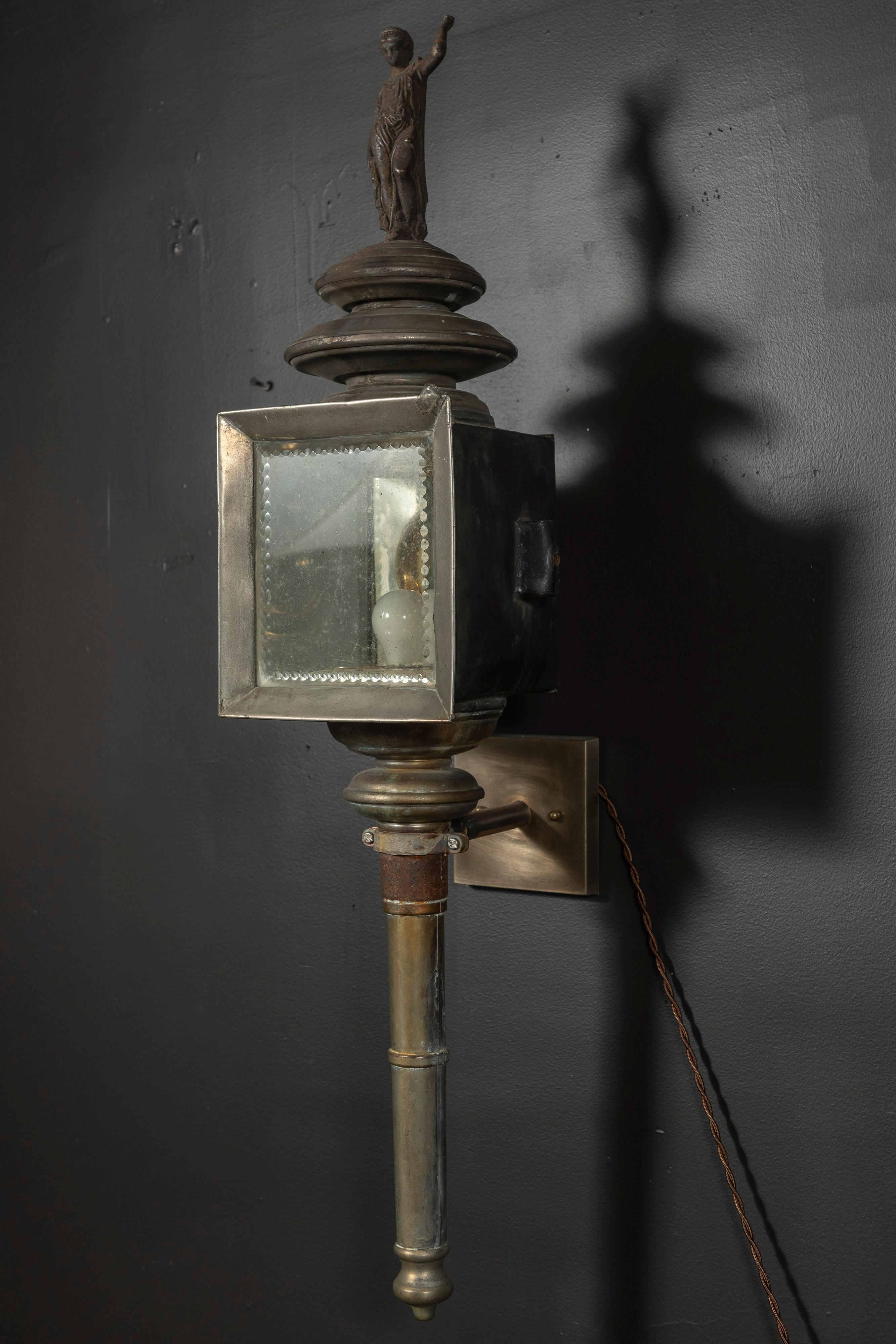 Pair of rare antique carriage lanterns in brass, mercury glass and metal with a classical figure enhancing the top. These lanterns may be installed in both interior and protected exterior locations, at an entrance or as wall sconces.