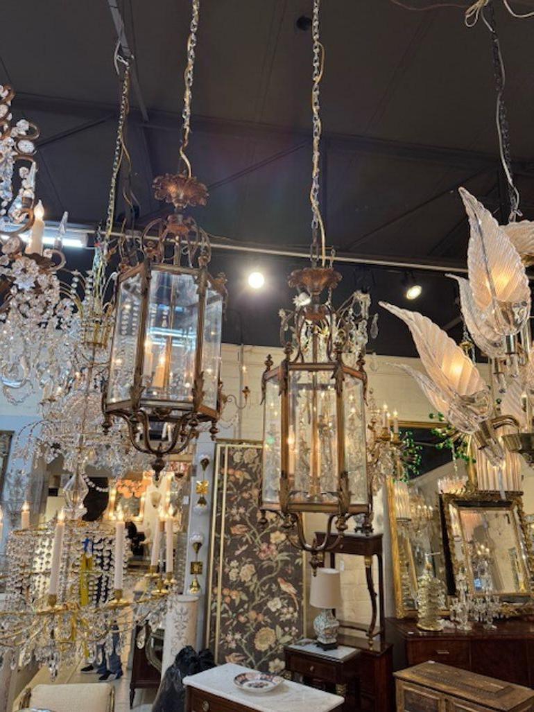 Ces lanternes anciennes en laiton et en verre, originaires d'Angleterre, présentent des détails décoratifs en forme de volutes et sont livrées par paire. L'utilisation de matériaux en laiton et en verre ajoute une touche d'élégance et de charme
