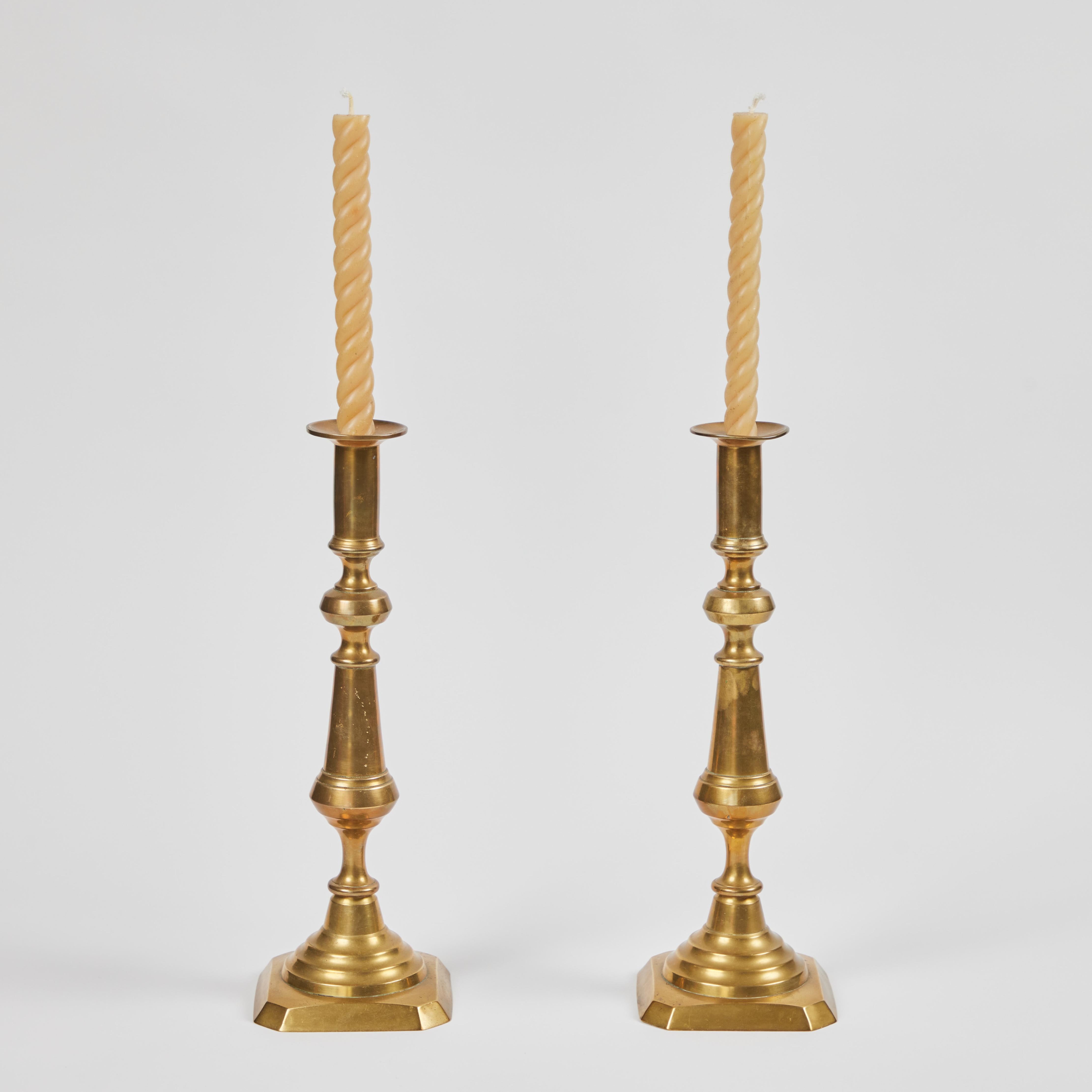 We love this pair of outstanding oversized antique brass candlesticks. They stand tall and are the perfect to accent to any table, side board or mantle. They have a wax pusher feature and display a beautiful rich natural aged patina finish. They