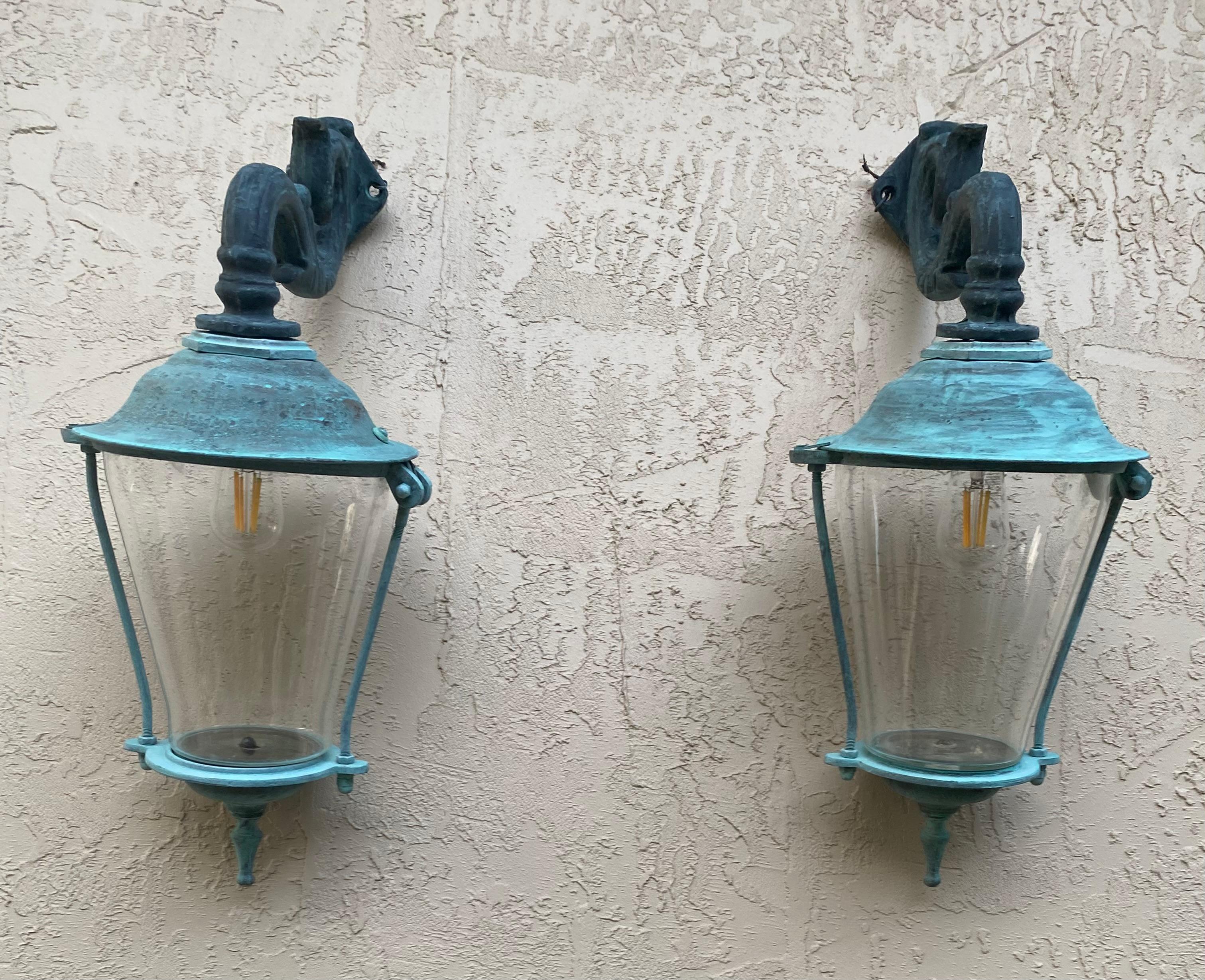Elegia la tua casa con l'eleganza senza tempo di questa eccezionale coppia di lanterne da parete in ottone antico. Questi affascinanti apparecchi vintage offrono uno sguardo su un'epoca passata, mostrando una squisita maestria e un design che fonde