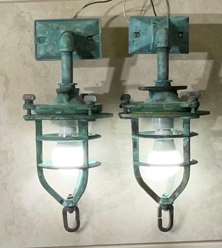 Queste affascinanti applique nautiche in bronzo, che probabilmente un tempo servivano come robuste luci di convoglio, sono una testimonianza della storia marittima e dell'artigianato duraturo. Immagina queste luci che adornano le paratie di
