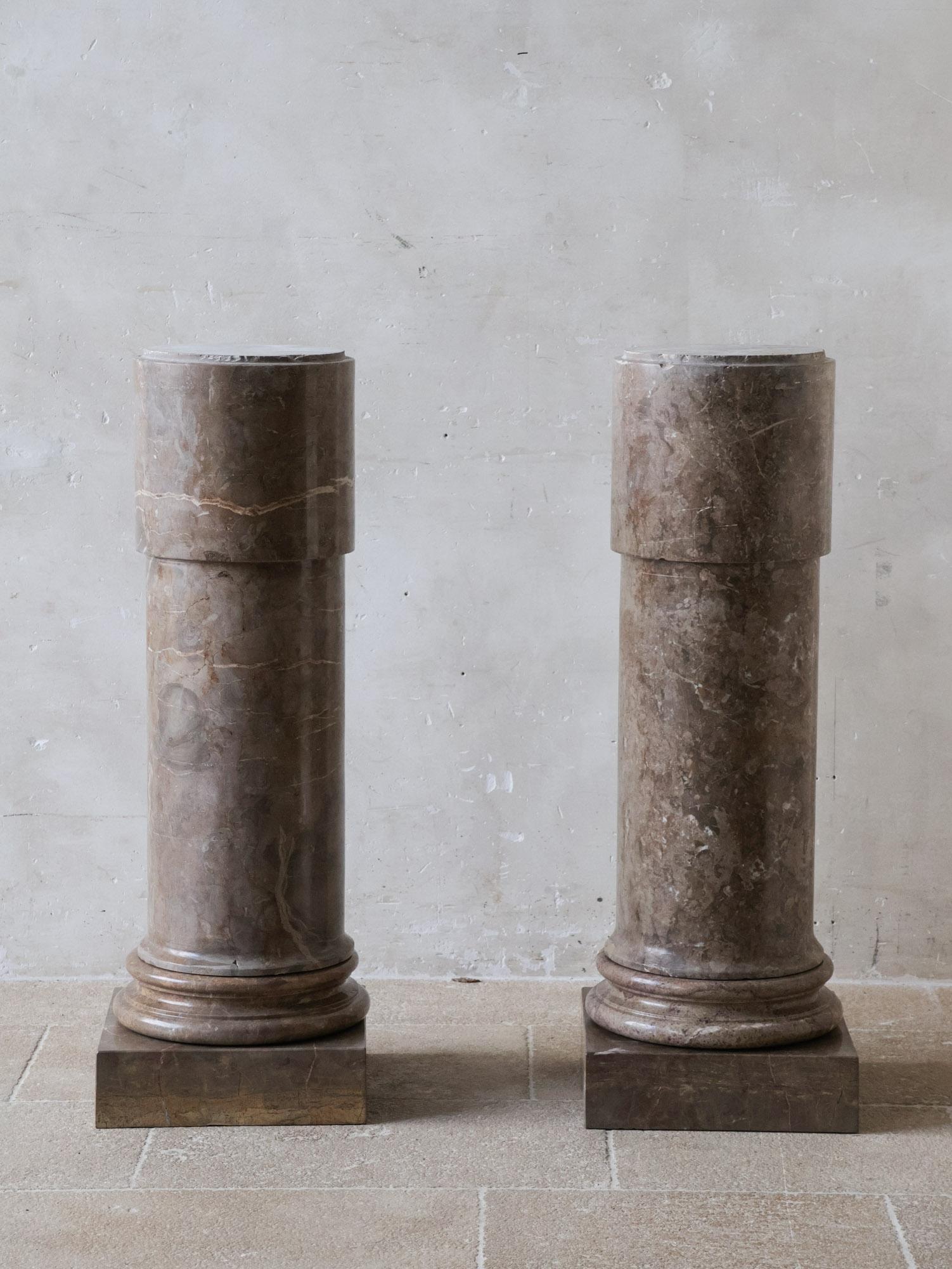 Elegant pair of solid marble columns in a soft, powdery brown tone with a brocatelle pattern and natural veining. Their warm coloring instantly conveys a luxurious and classical appearance.

Each column is constructed from three distinct parts: a