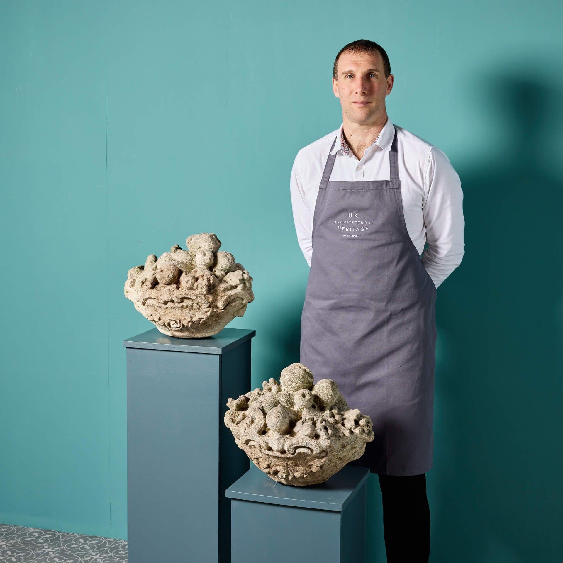 Paire de paniers en pierre calcaire de forme ovale, sculptés et ornés de fruits. Ils ont été récupérés dans un jardin du sud de Londres. Cette paire est dans un état joliment altéré, avec de nombreux détails ; parfait pour un jardin de campagne ou