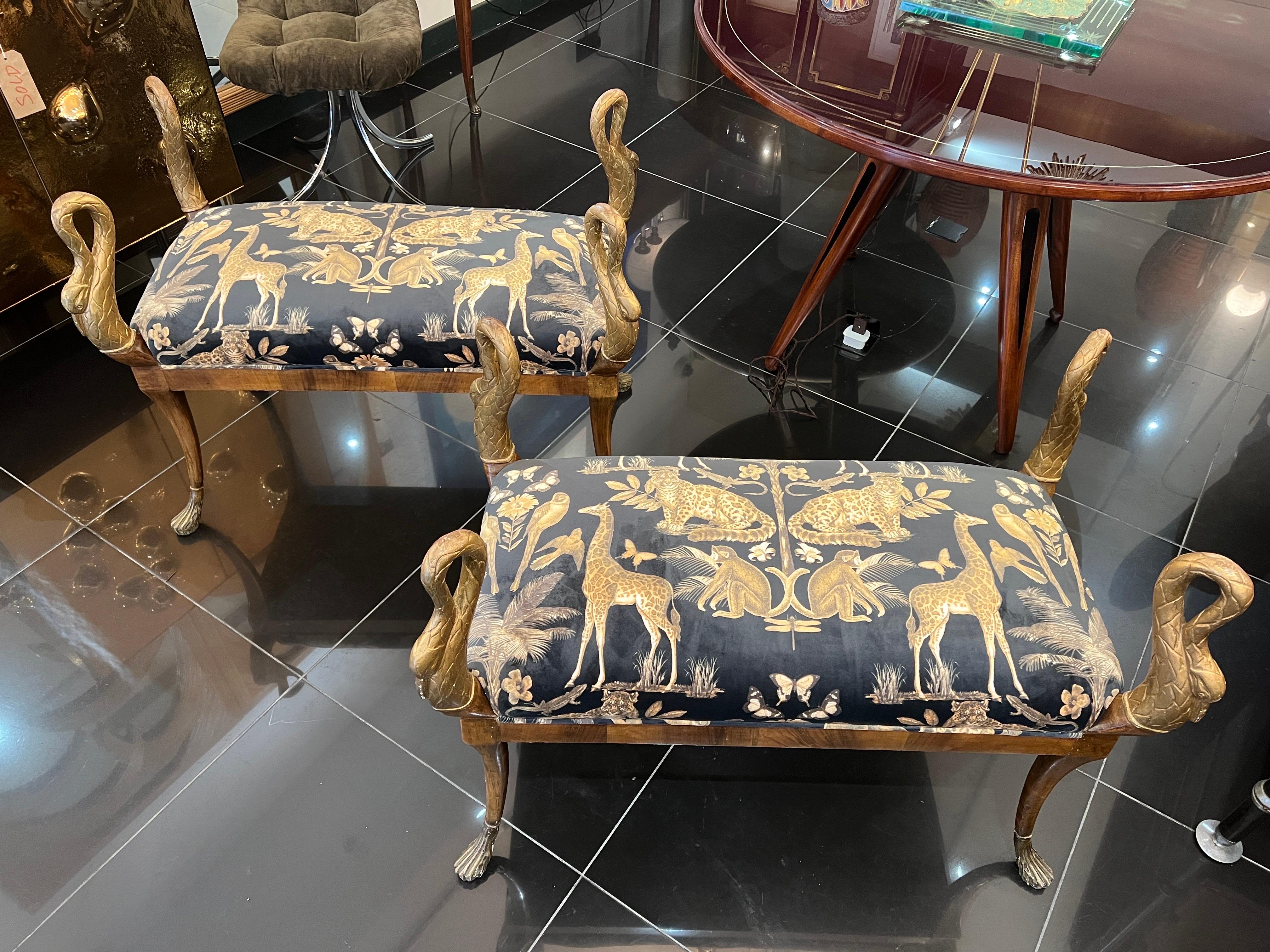A pair of empire hand carved walnut with gilded swan heads and feet benches beautifully upholstered in animal motif velvet .