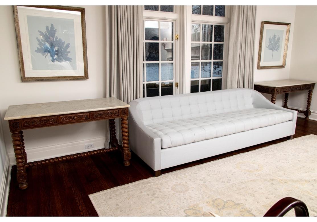 Fine pair of carved walnut library tables with marble top featuring carved frieze drawers on barley twist legs and stretcher with carved square medallions on bun feet. One table has two frieze drawers and the other has only one. Marble tops are