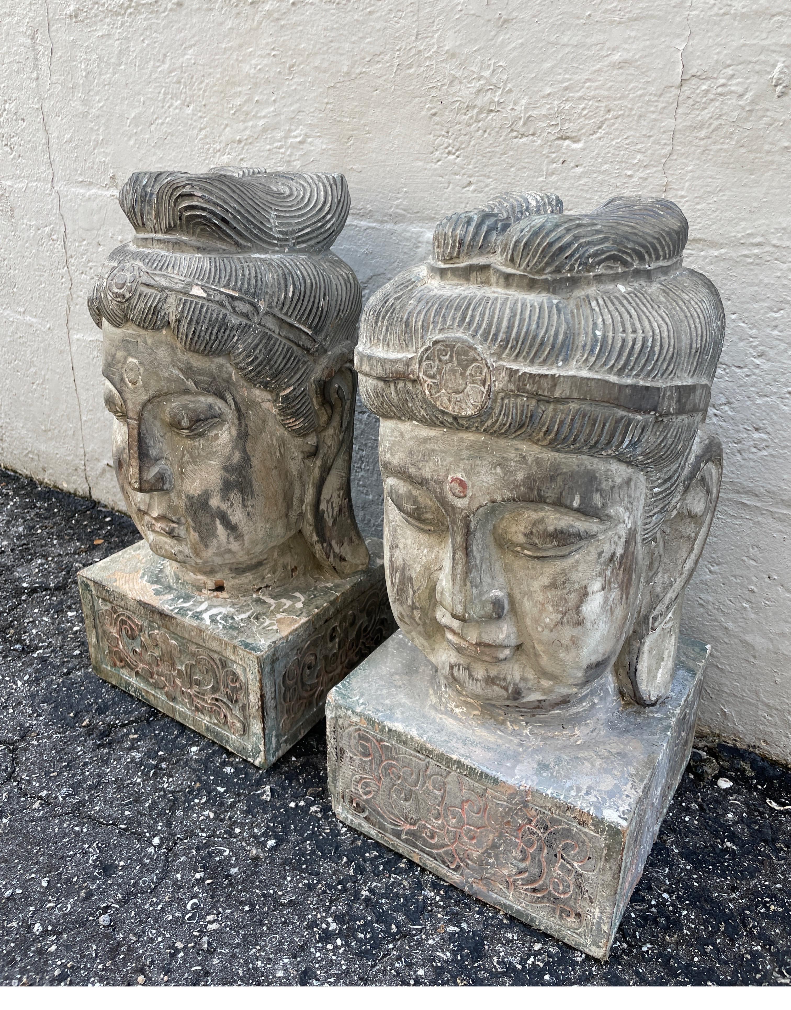 Paire de grandes têtes de bouddha en bois sculpté avec des restes partiels de peinture.
