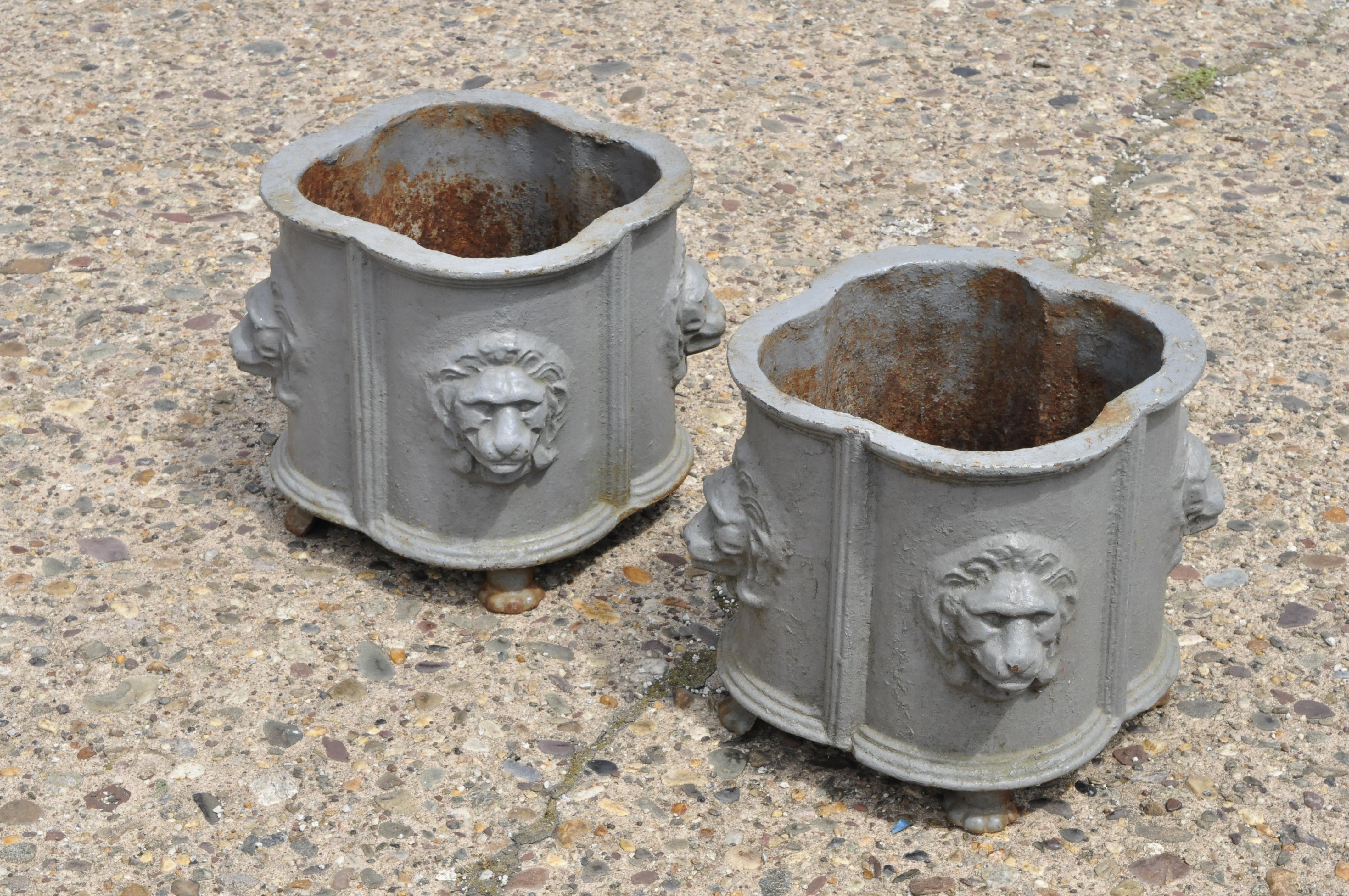 Pair of antique cast iron French Empire style planter pots with lion heads. Items feature lion heads, paw feet, cast iron construction, quality craftsmanship, great style and form, circa mid-20th century. Measurements: 10.5