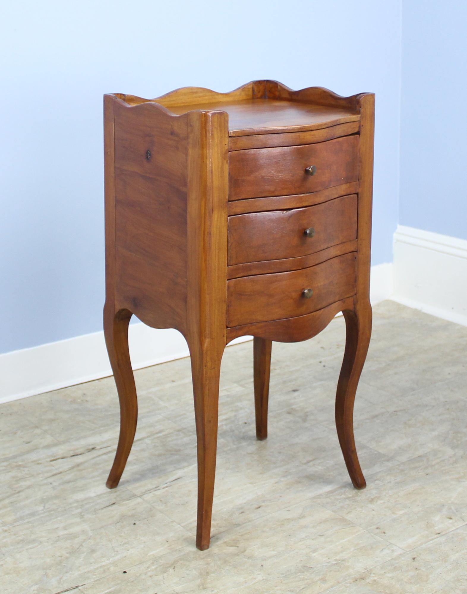 A pair of fine charming cherry nightstands with three sweet drawers and gracefully curved cabriole legs. The tops are in very good condition, with a small gallery on three of the four sides. Wonderful vibrant color and good cherry grain.
