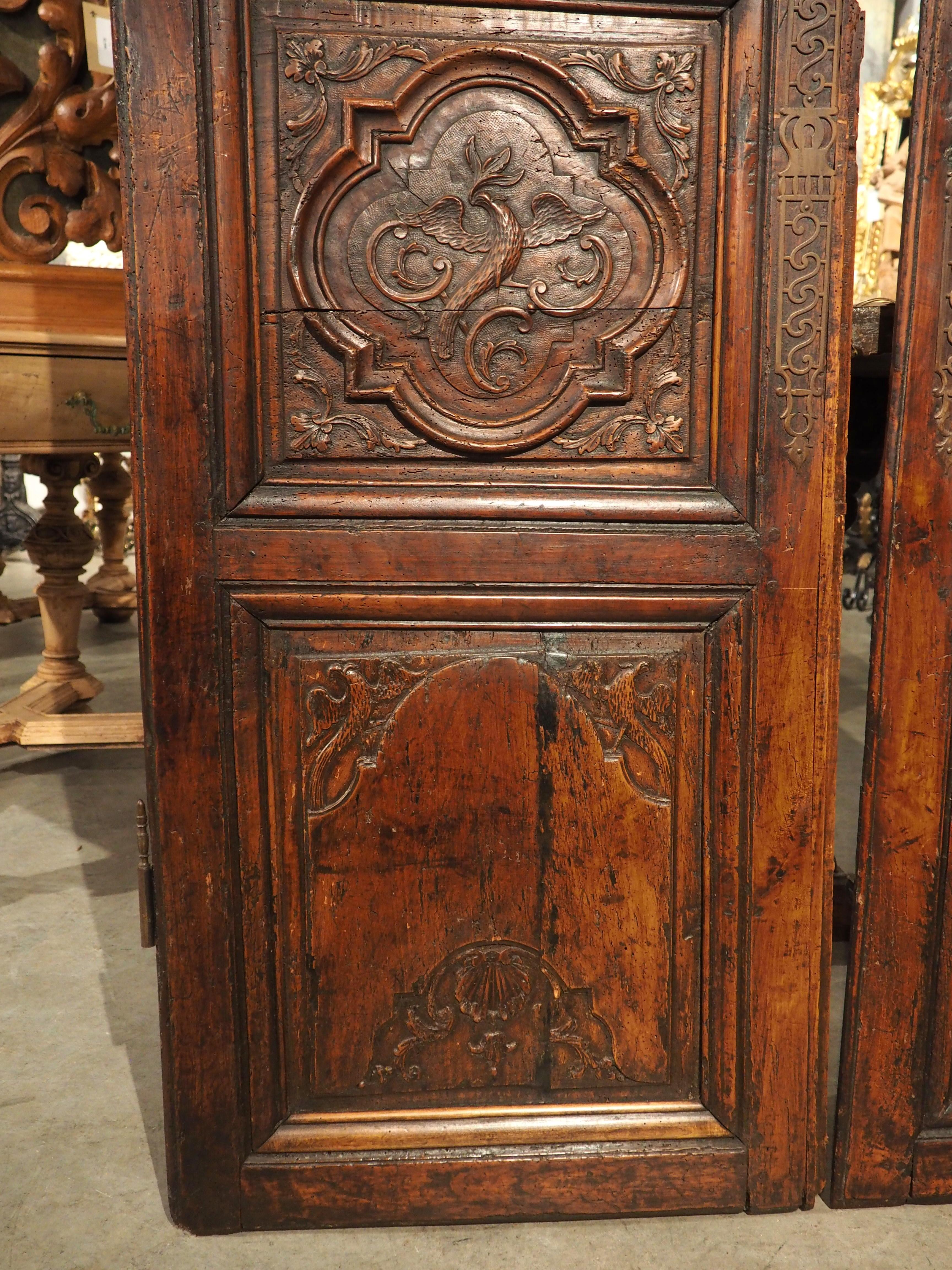 Originally carved in Rennes, France, circa 1720, these avian and foliate-themed doors would have graced the front of a period Regence cherry wood armoire. Both doors have been carved with three panels surrounded by thick molding. Several