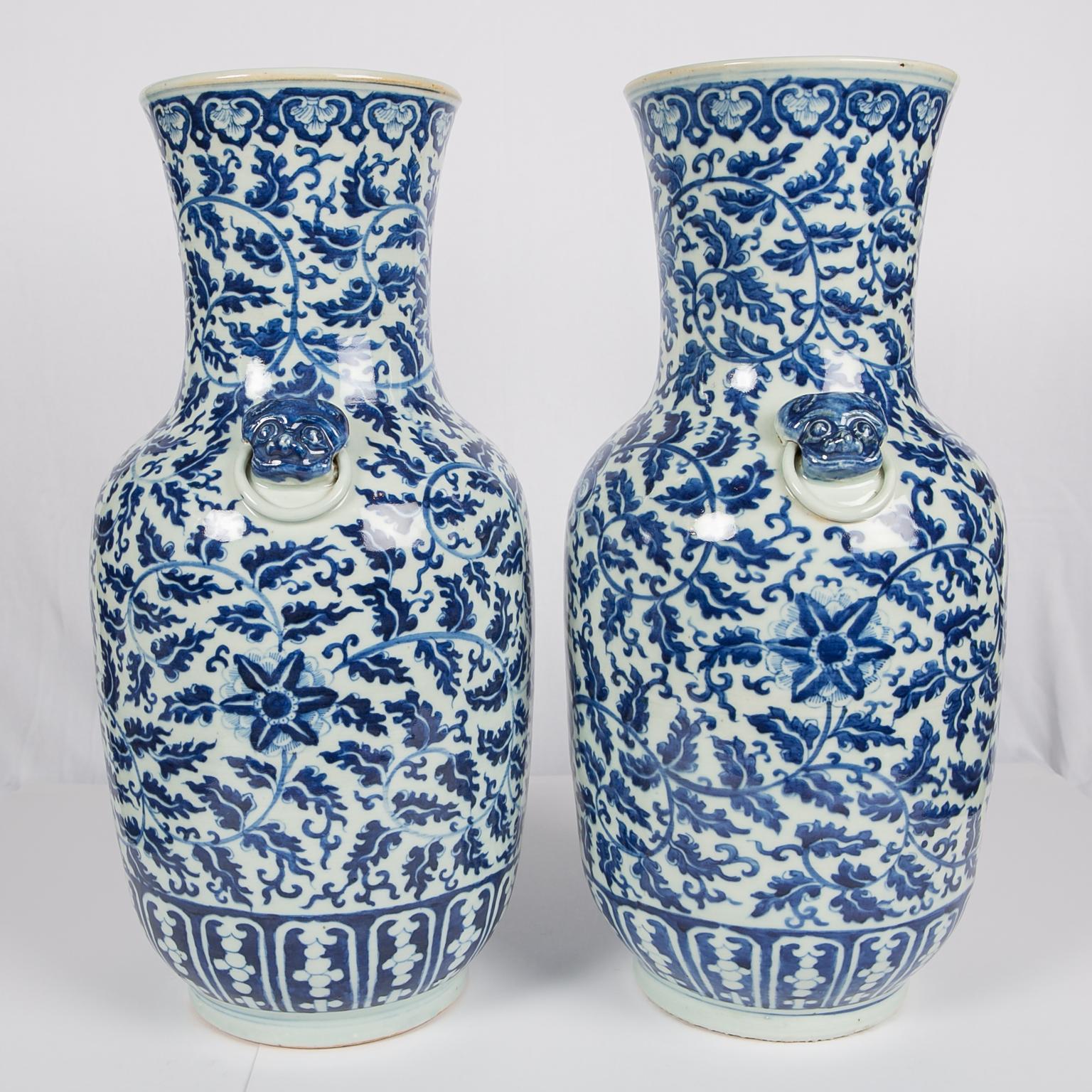 A pair of Chinese blue and white porcelain vases with an overall design of scrolling vines. Along the bottom are lotus panels. A band of ruyi-shaped floral patterns adorn the top. Two lion-head handles are attached to each vase.
Made in the Qing