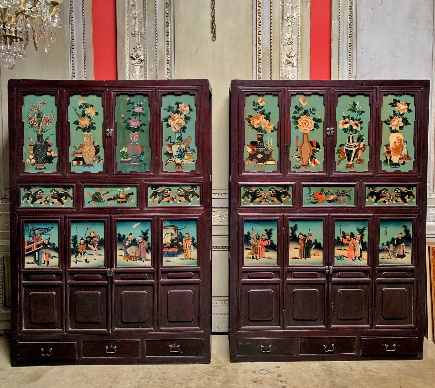 A pair of antique Chinese cabinets in elmwood with reverse painted glass planels depicting the four seasons. These early 20th century cabinets are highly decorative and colorful with a feel of chinoiserie.
