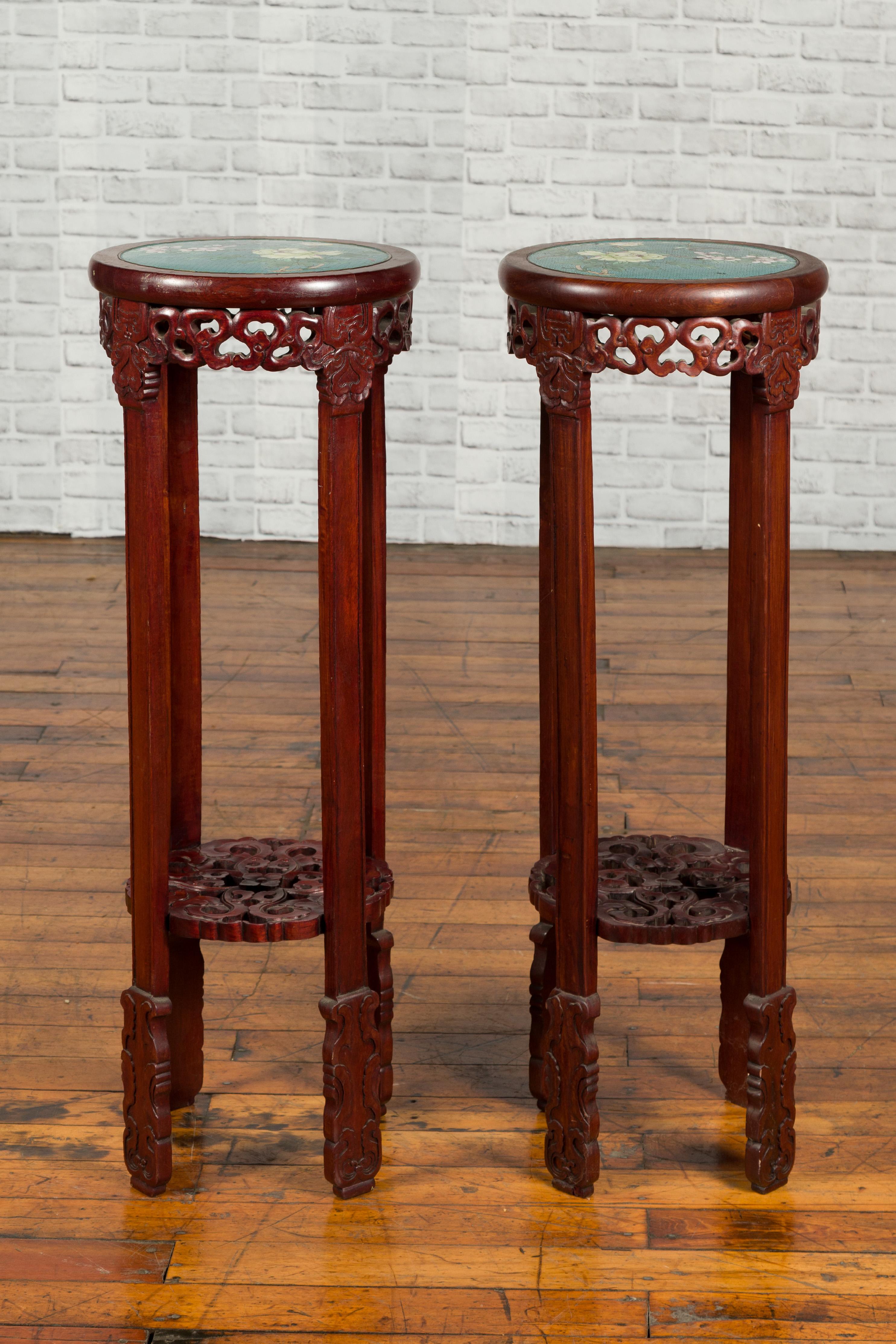 A pair of antique Chinese stands from the early 20th century, with painted floral and bird decor and carved aprons. Created in China during the early 20th century, each of this pair of wooden stands features a circular top adorned with an exquisite