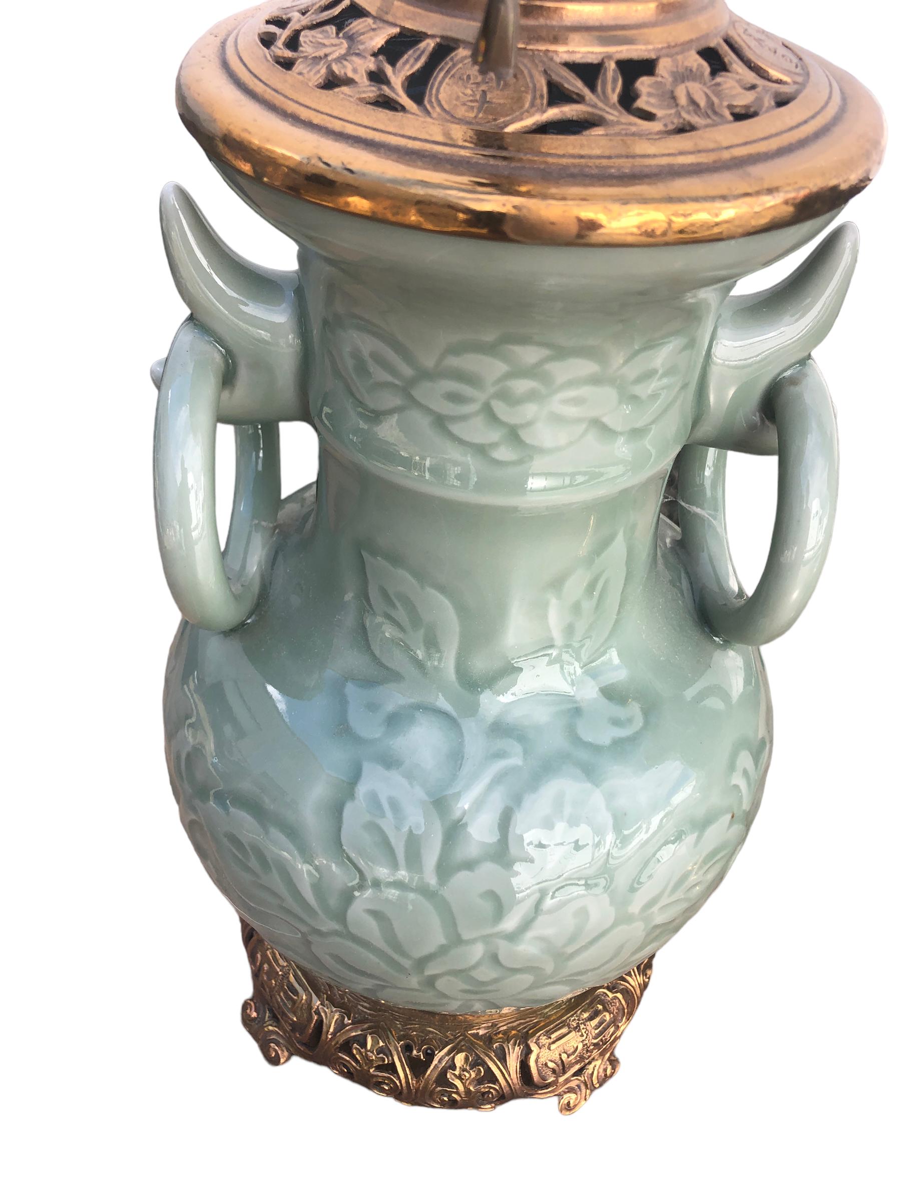 A fine pair of antique Chinese celadon lamps with raised foliate design and large applied rings. Lamps are mounted with Chinese bronze fitting. Lamps were probably electrified in the 1920’s and the mounts date from that period. Wired and in good