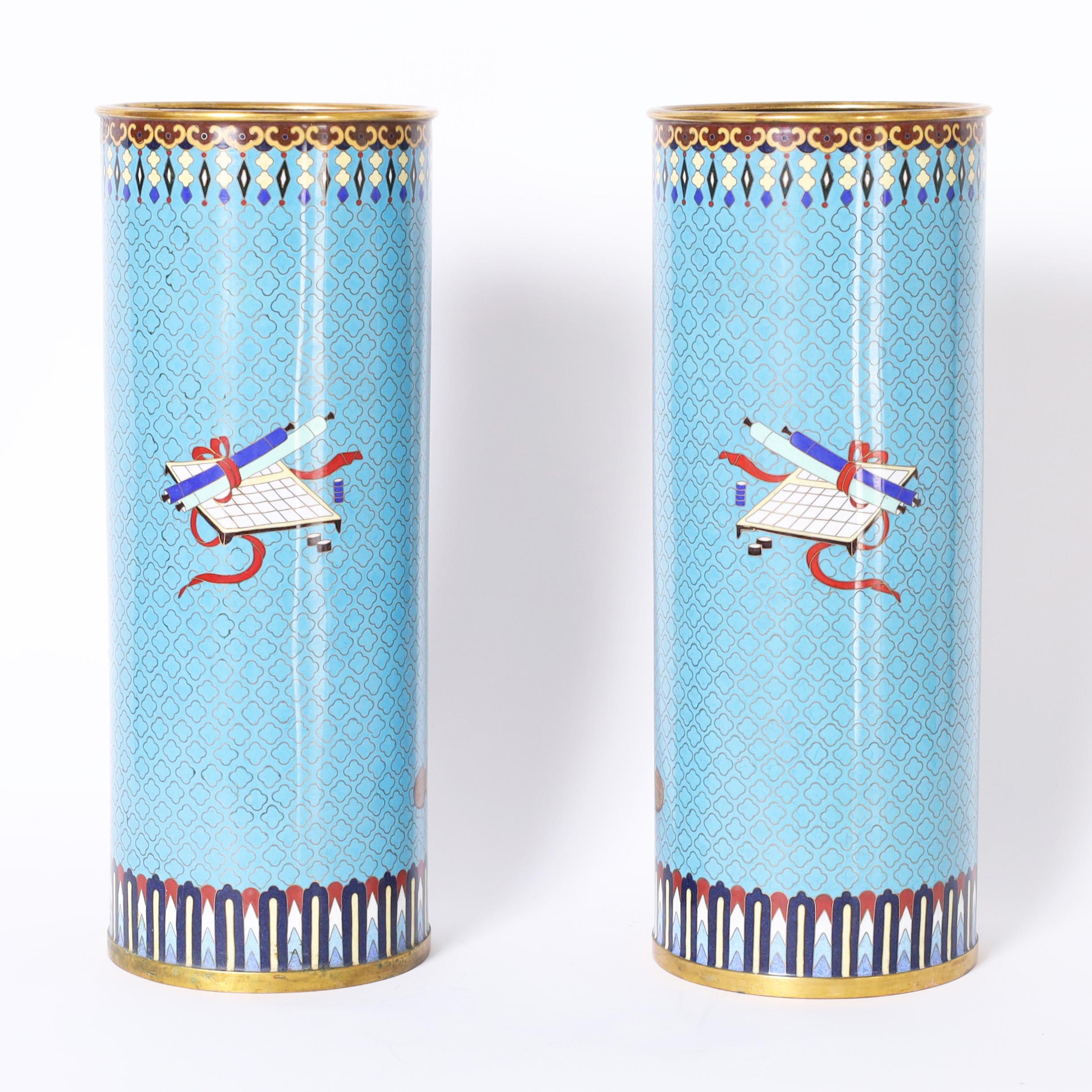 True pair of antique Chinese cloisonne vases decorated in an unusual composition depicting flowers in a stand against an alluring blue field with geometric borders.