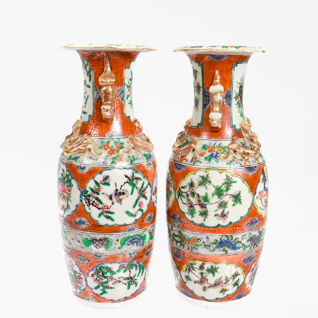 A fine pair of antique Chinese export porcelain vases.

In the Rose Canton or Famille Rose style.

Decorated throughout with numerous cartouches of flowers and birds in a variety of green, blue, purple, pink, and yellow tones on a dark orange 'fish