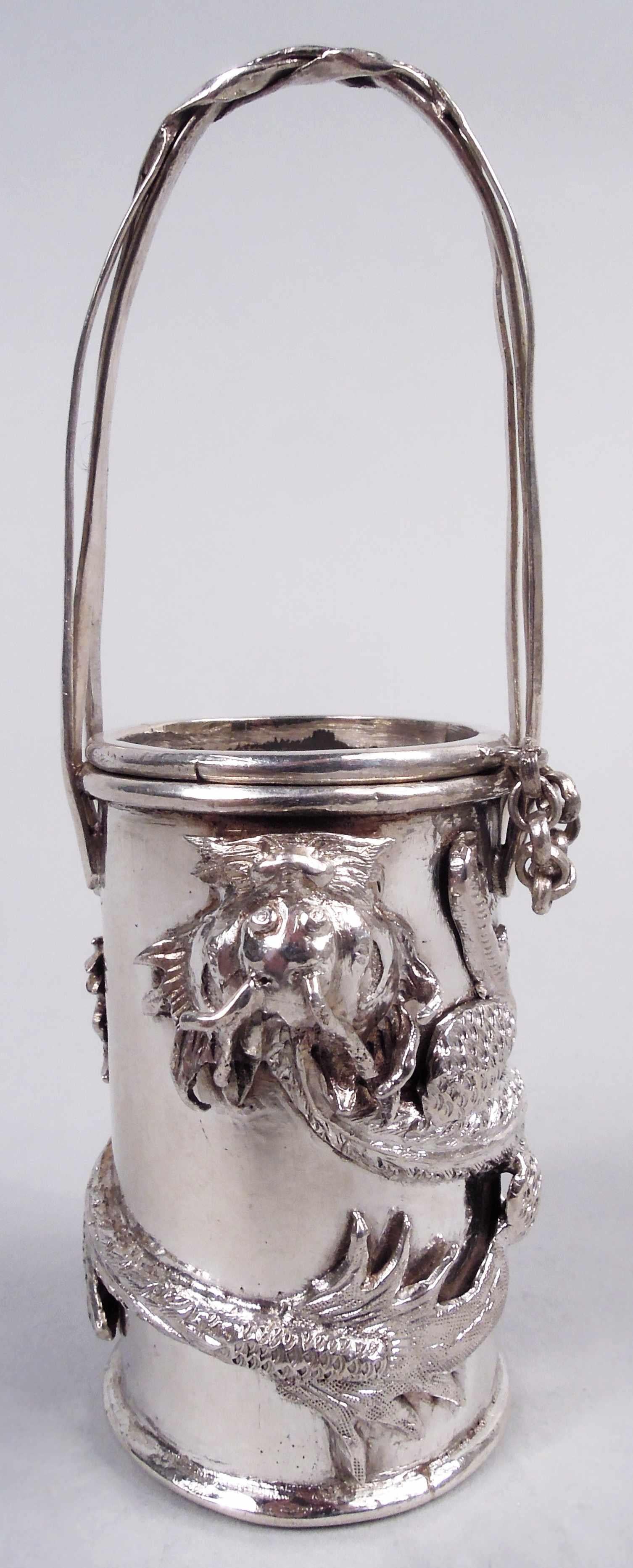 Pair of Chinese export silver mustard pots, ca 1890. Each: Cylindrical with fixed and entwined ratan-style handle; cover chained with inset and engraved diaper top. Applied wraparound horned and taloned dragon. For piquant condiments. Marks include