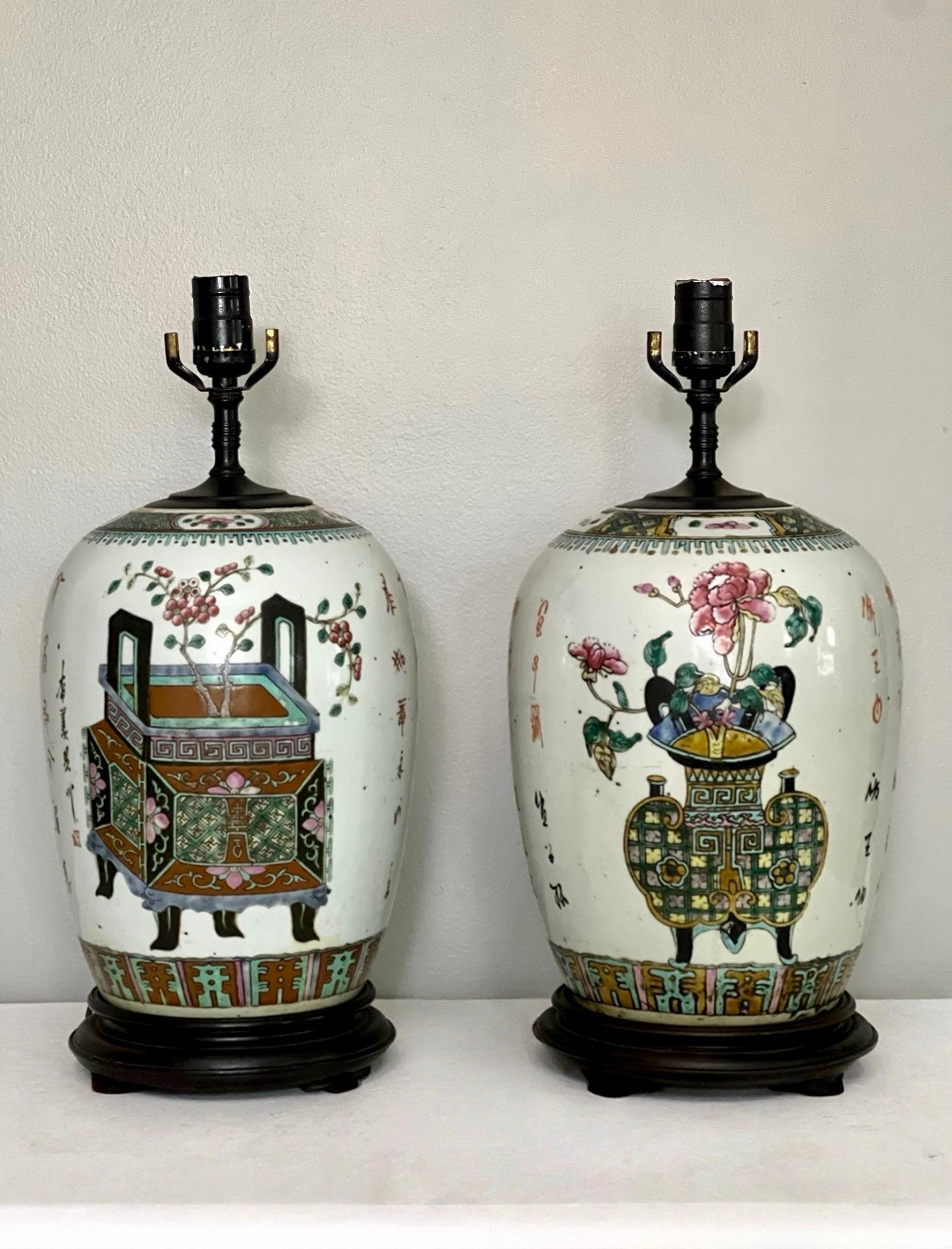 Pareja de lámparas de jengibre Famille Rose pintadas a mano de finales del periodo Qing, China, hacia 1900.  Cada uno está decorado con esmalte policromado con diferentes incensarios antiguos y vasijas rituales llenas de peonías en flor y bonsáis en