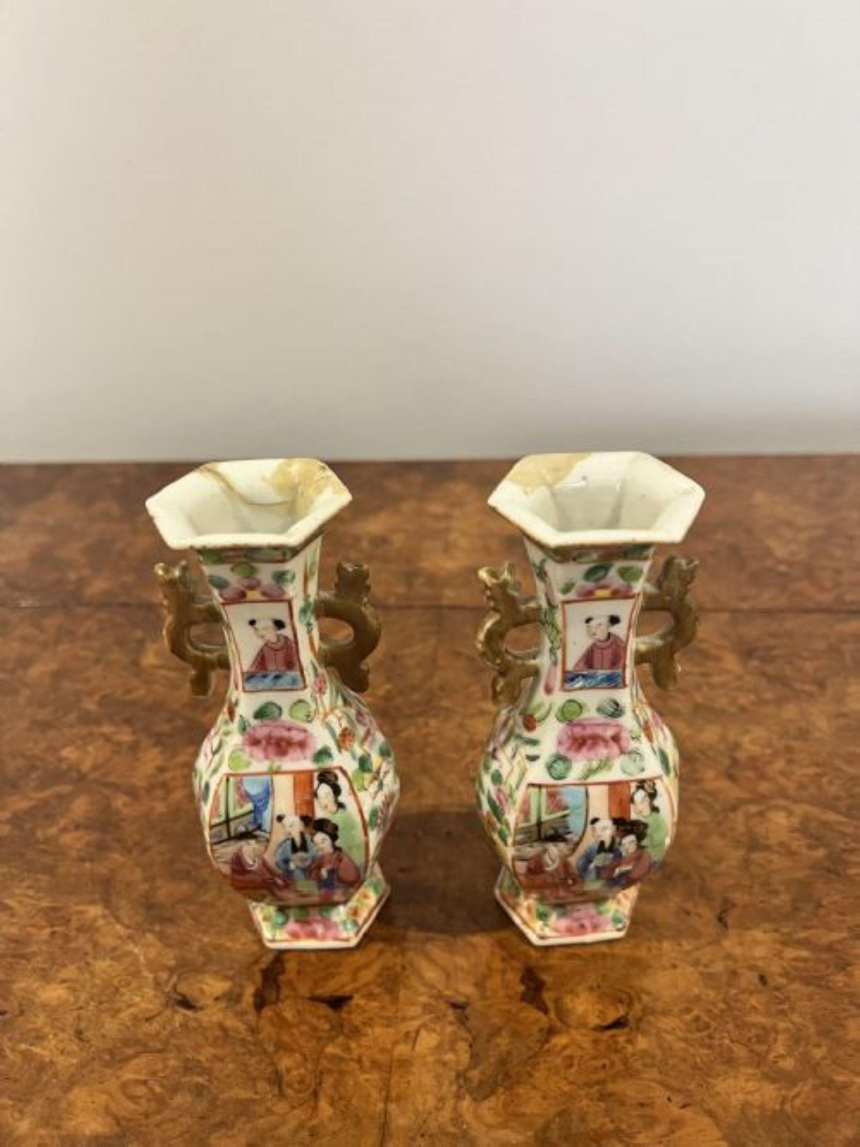 Pair of antique Chinese famille rose small vases having shaped handles to both sides decorated in figural panels on a ground of precious objects in wonderful green, blue, pink, gold and white colours. Restoration to the tops as shown.