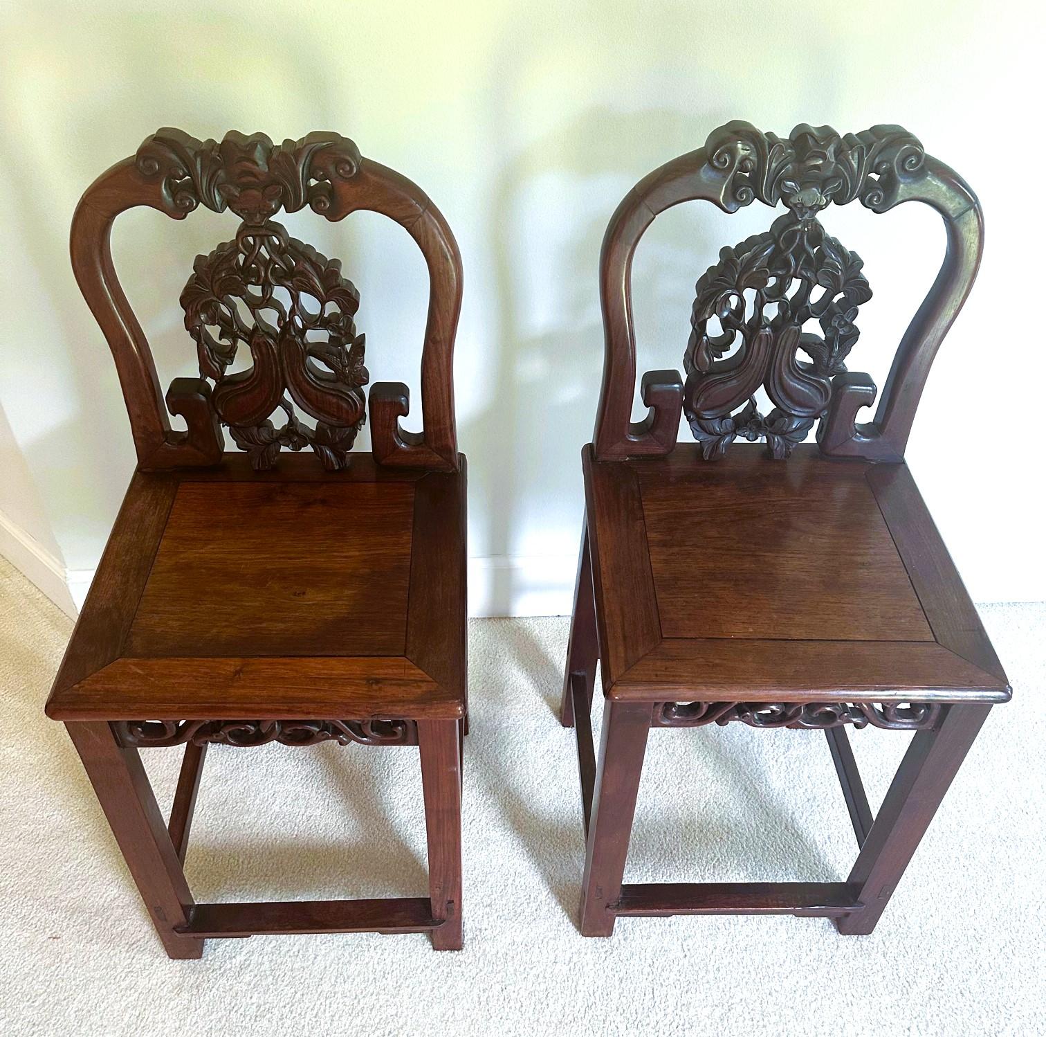 A pair of antique Chinese side chairs circa 19th century, late Qing Dynasty. Made from highly grained Hong Mu, a hard wood that resembles the Chinese rosewood, Huanghuali. These chairs feature a craved back support with longevity symbols such as