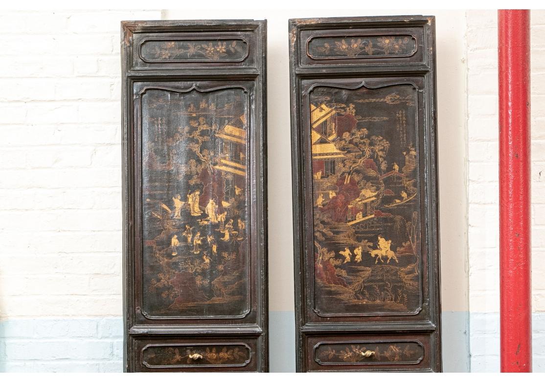 Tall black lacquered carved door panels with two large decorated shaped sections above and below in gilt and dark red, framed by smaller floral ones. The top panels illustrate pavilions amidst trees with various figures, one on horseback, as well as
