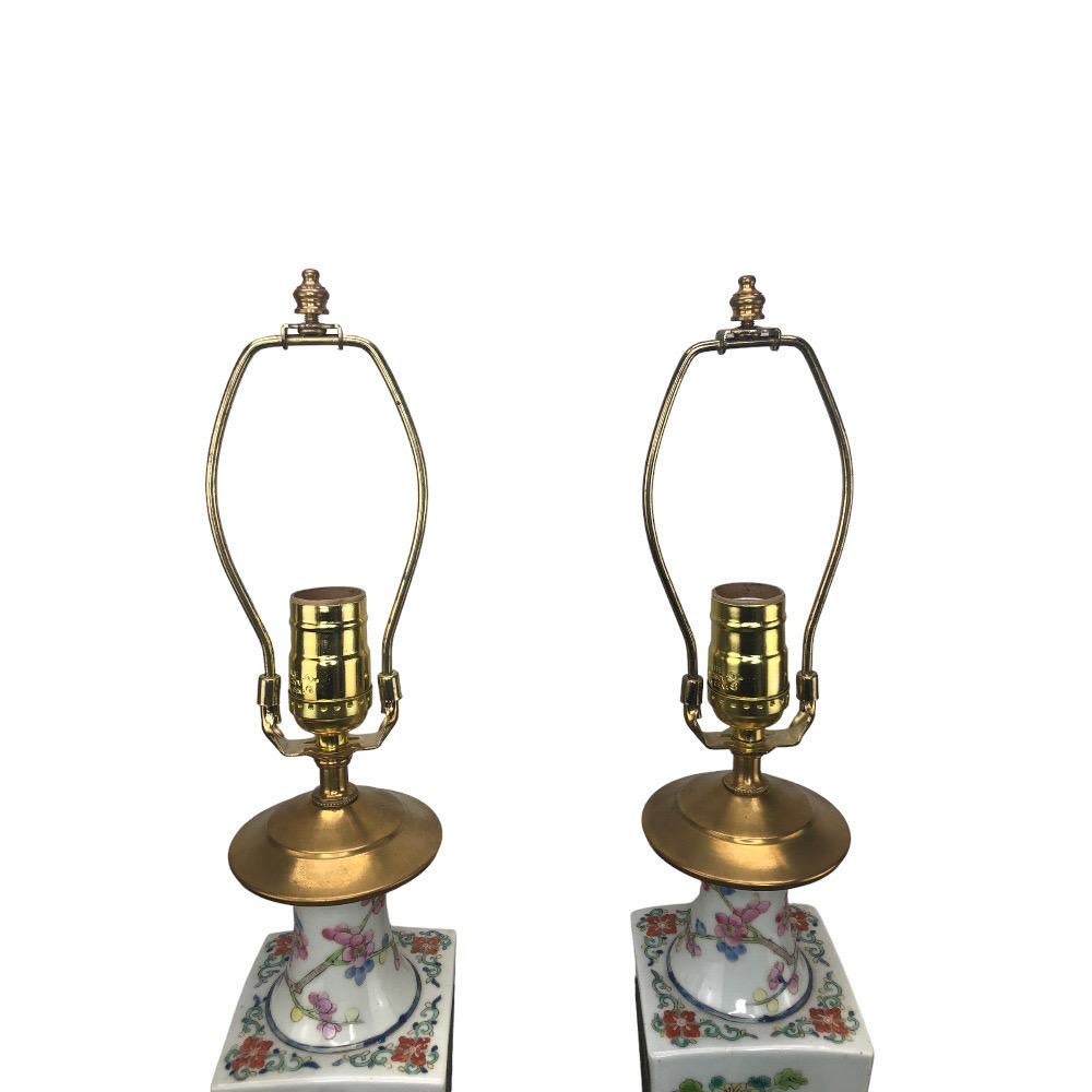 Pair of Chinese porcelain vases mounted as lamps. Square tapering vases with alternating panels with floral decorations on a white background. Mounted on mahogany colored bases. Wired and in working condition.