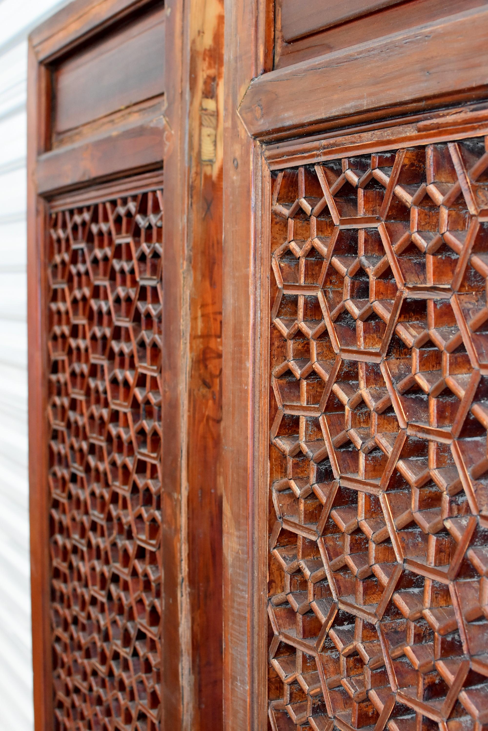 This is a pair of beautiful, 19th-early 20th century Ming style Chinese antique door screens. The main section of the screen is formed by an octagonal flower design, which are created by joining custom-cut pieces of wood using tenons and mortises,