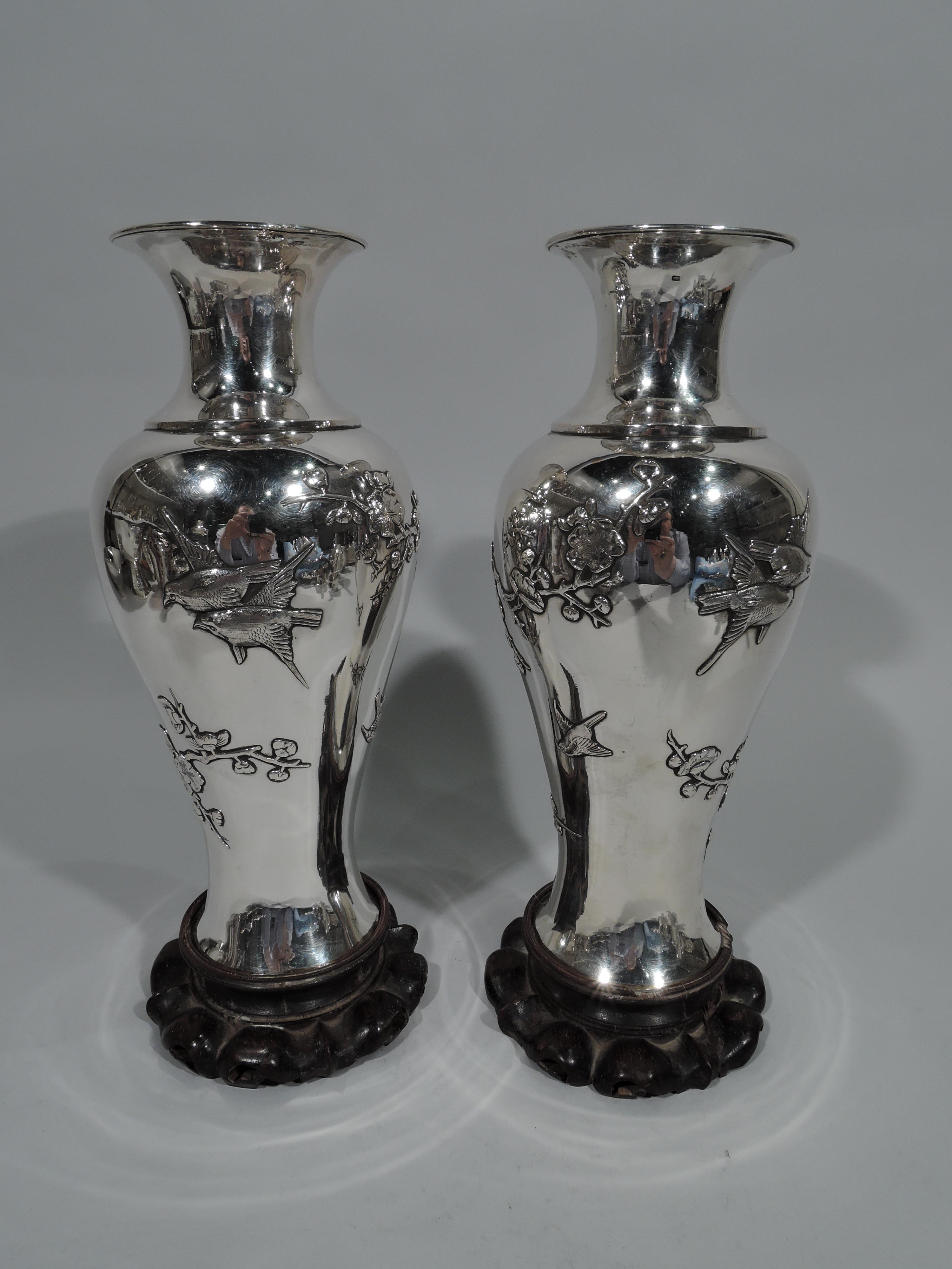Pair of Chinese silver vases, circa 1900. Each: Baluster with spool neck and flared mouth. Applied and engraved ornament: Winding, craggy blossoming prunus branches and perched and flying birds. Stained rosewood mount. Chinese characters marked on
