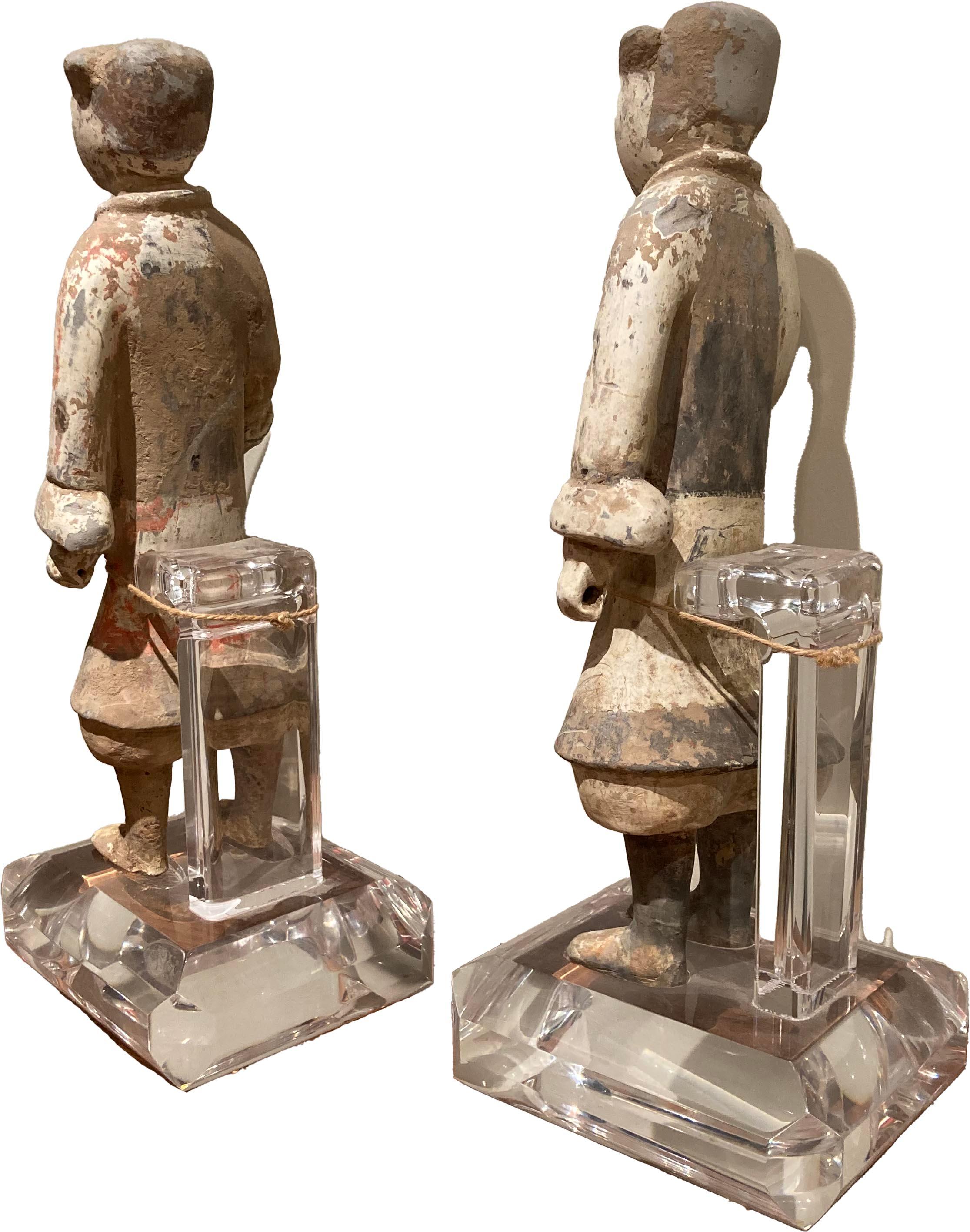 Pair of Terra Cotta soldier burial figurines on lucite bases. These are two well-preserved figures with some paint chipping and ware - painted white and grey. Created in the style of the Han Dynasty.