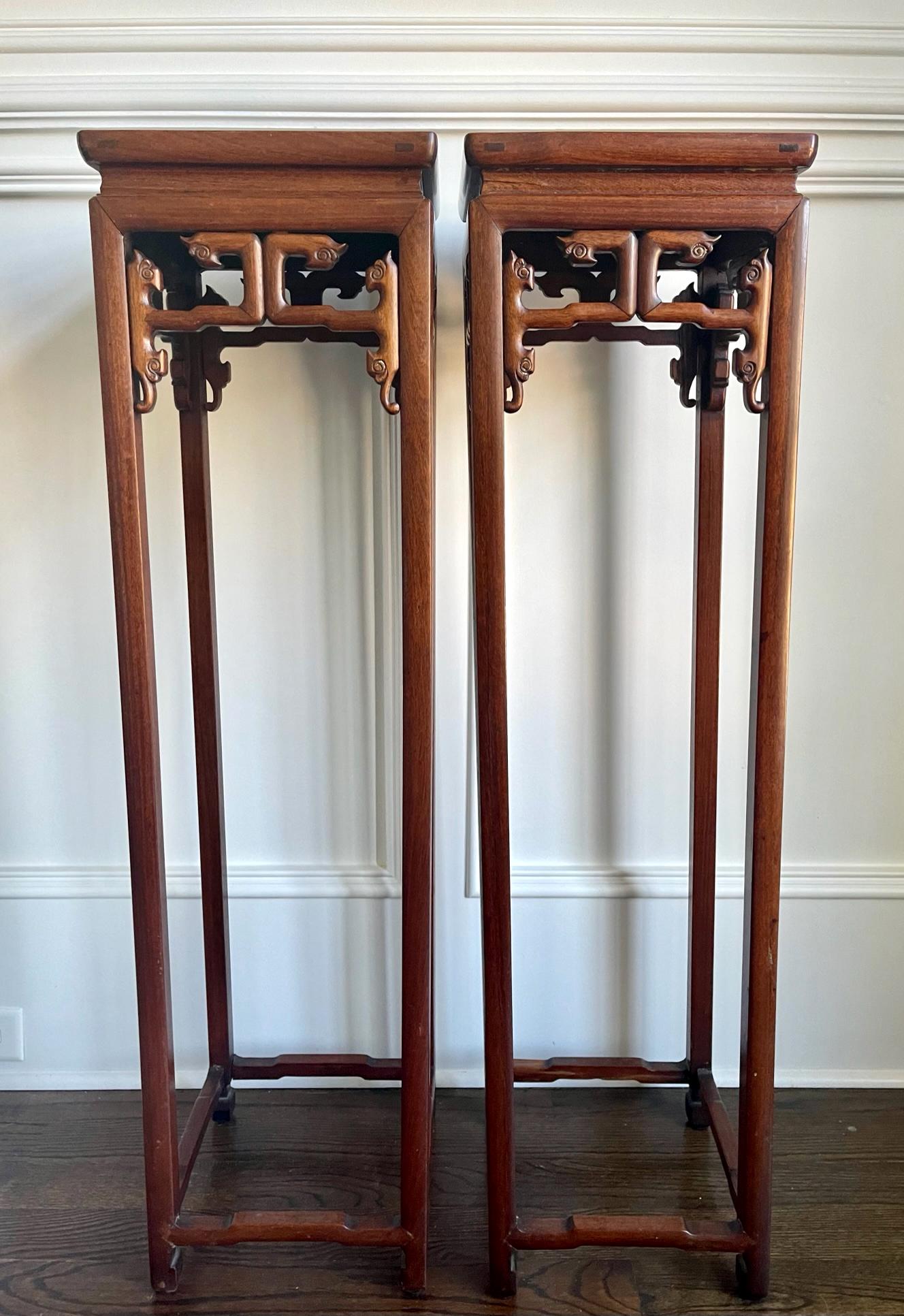 A pair of tall Chinese pedestal stands circa 19th century the late Qing dynasty. These types of stands were traditionally used to display vases or planters in the hall of the residence of wealthy Chinese. The pair of stands was made from hardwood of