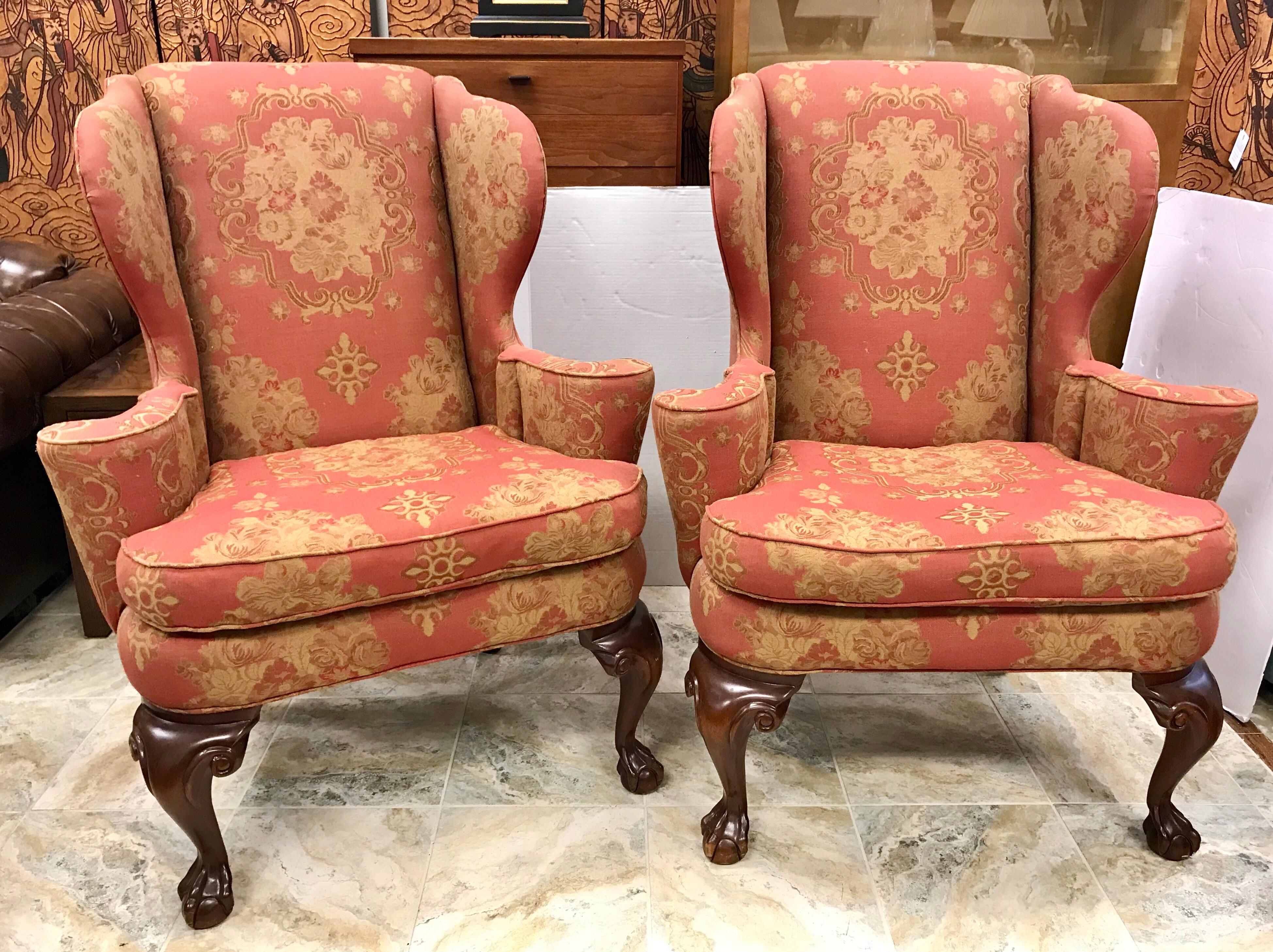 Gorgeous pair of antique Chippendale wingback arm chairs done in an elegant salmon and gold fabric.