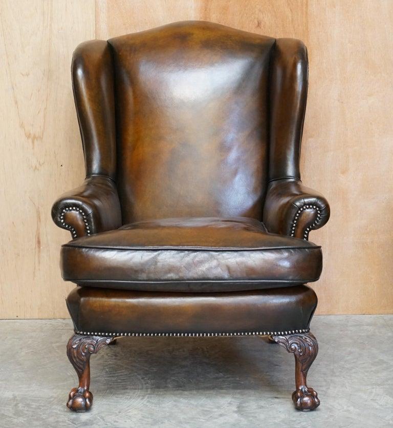 Nous sommes ravis d'offrir à la vente cette paire de fauteuils Wingback entièrement restaurés, en cuir brun teint à la main, avec des pieds sculptés en forme de griffe et de boule.

Il s'agit d'une paire de chaises de très bonne facture et de
