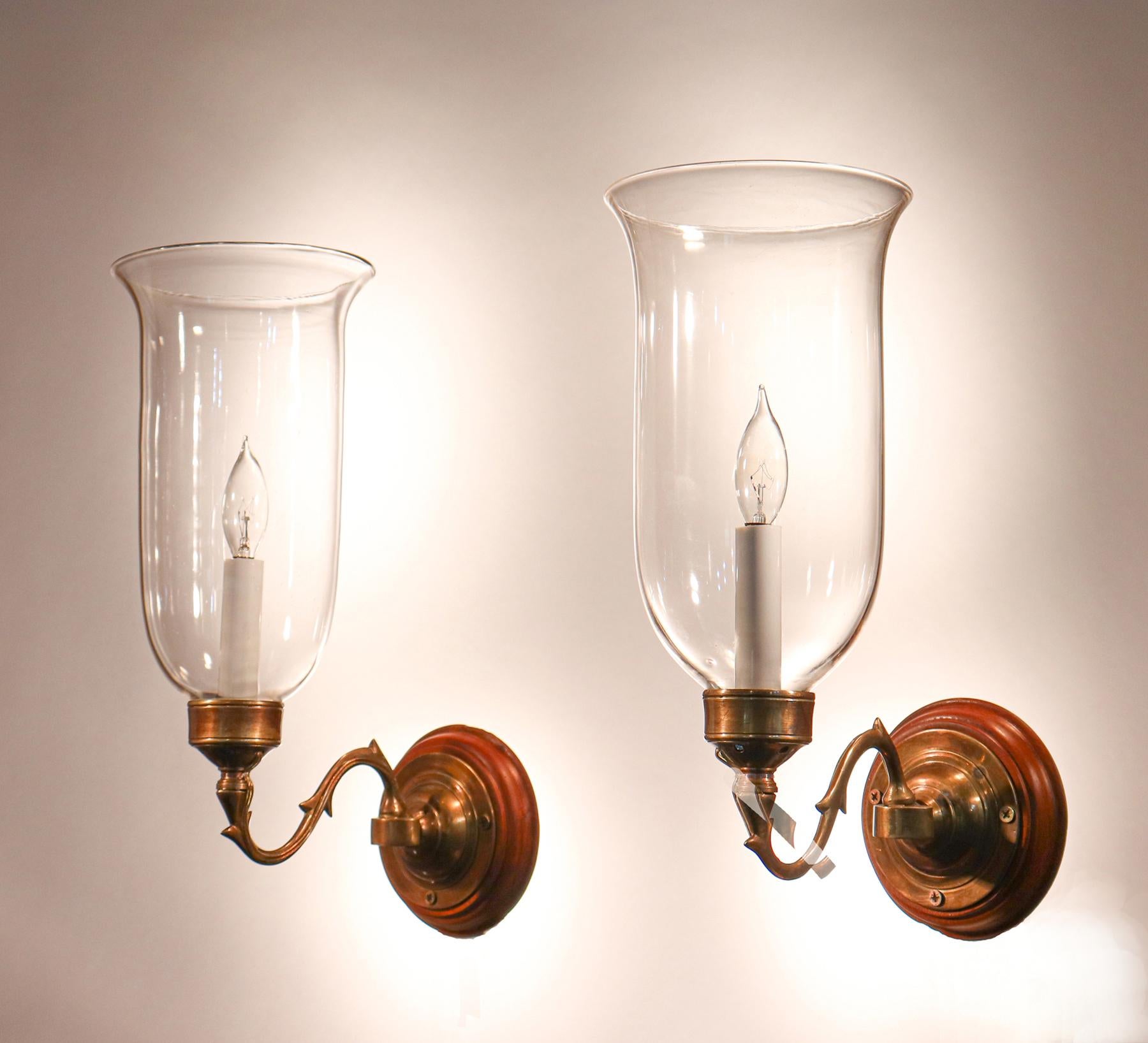 Pair of superb quality hand blown glass hurricane shades from England, circa 1880. These flared shades have classic form, and are well-suited for the projection of the custom-fabricated brass sconce arms. The sconce arms and mahogany backplates are