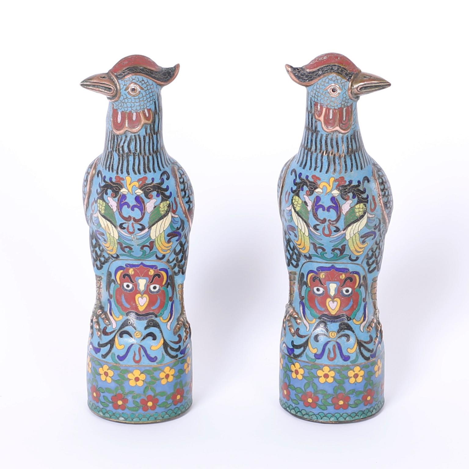 Lofty pair of antique cloisonné birds crafted with copper and
decorated with multi-color enamel designs of fauna and flora over a
blue field.