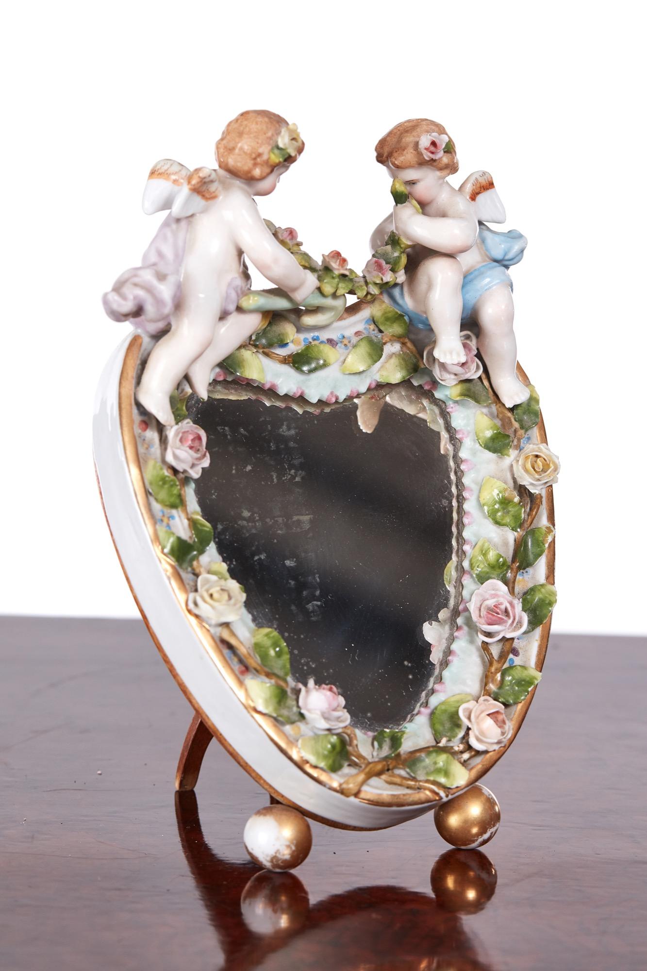 A charming pair of antique continental porcelain heart shaped mirrors on easel stands with a very attractive foliate decorated edge surmounted by two delightful cherubs.

  