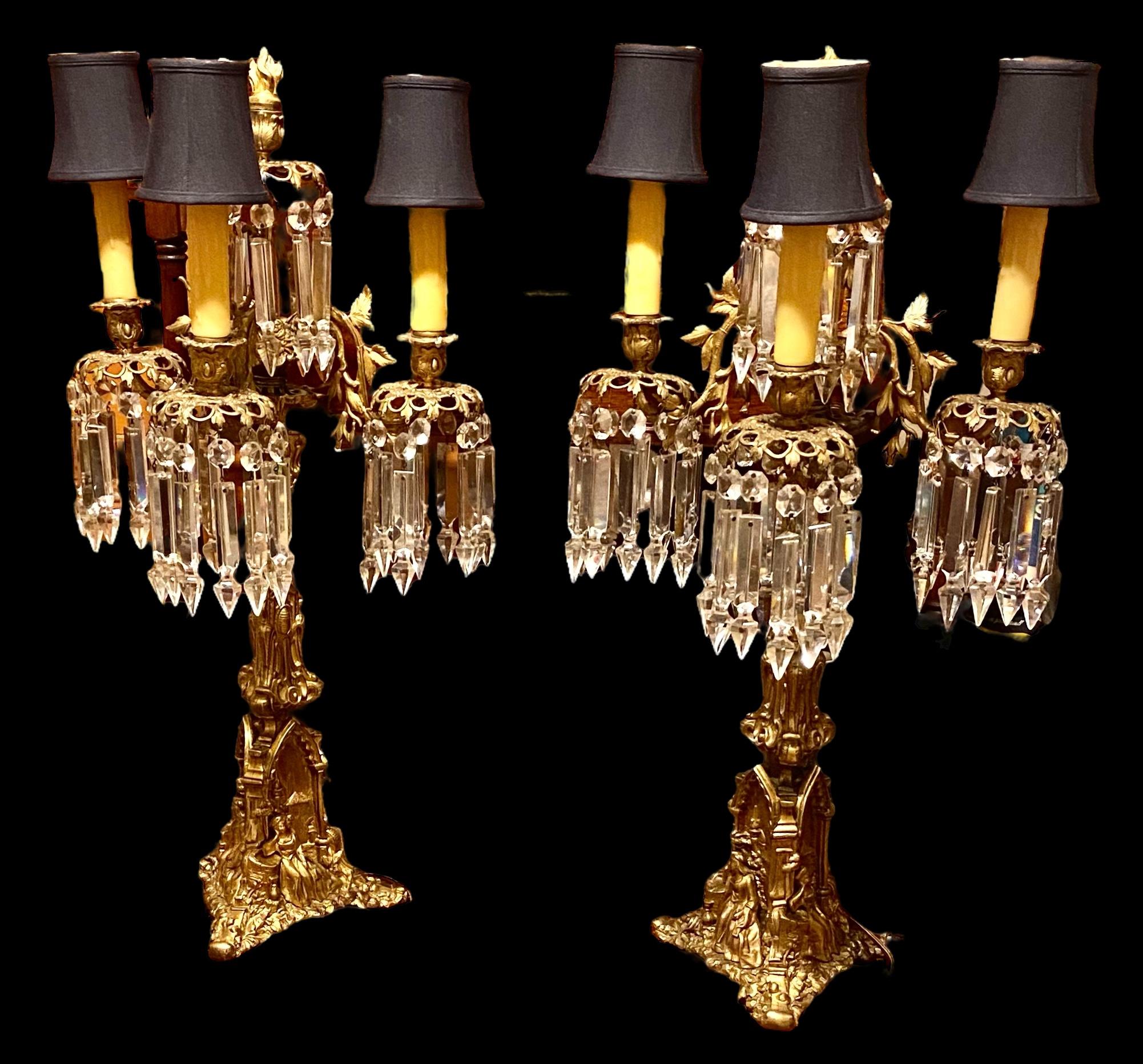 An exquisite, period pair of antique Cornelius and Company gilt bronze three arm candlesticks, Philadelphia, circa 1840, having been electrified sometime in the early 20th century. The pair standing on tripodal bases with gothic arches over a seated