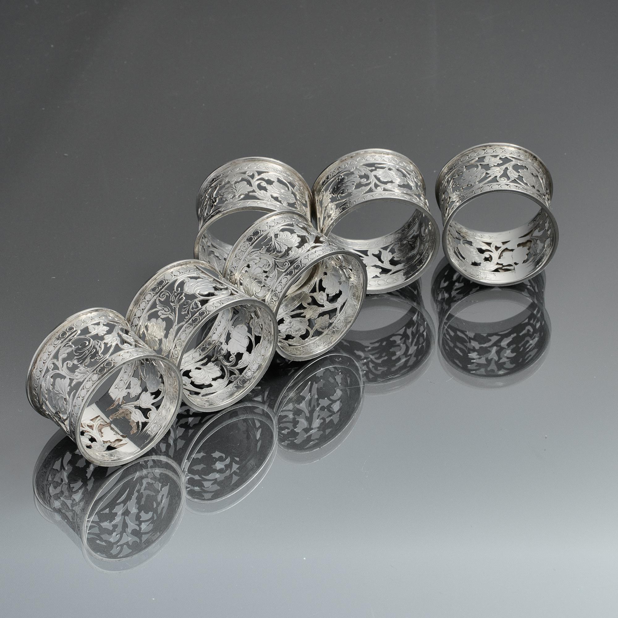 Lovely set of six antique, hand-pierced and engraved silver napkin rings made at the beginning of the Edwardian period. The decorative piercing features trailing foliage between two bands of scrolling roundels and each ring bears an applied silver