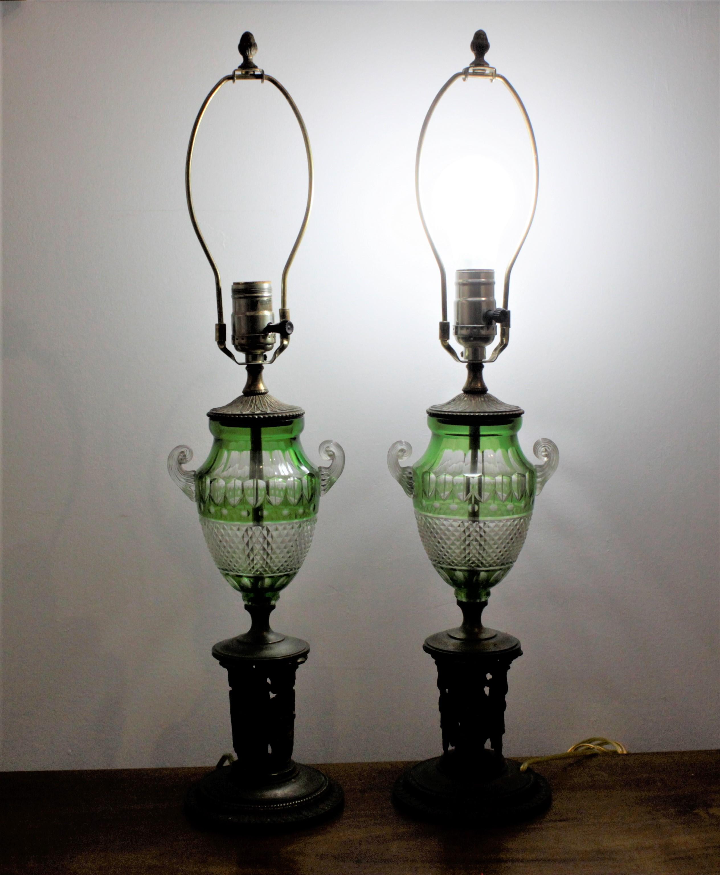 This pair of antique green cut to clear table lamps most likely originate from Bohemia, currently the Czech Republic, and date to circa 1890. These lamps feature a deep green cut to clear central font with a diamond pattern on the bottom portion