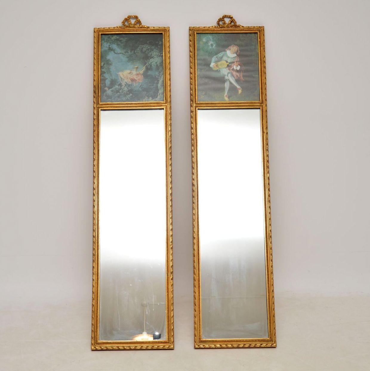 Pair of antique giltwood mirrors with decorative panels on the tops and in good condition. The gilt work seems all original with a nice soft color and very slight natural ageing. They have decorative bows on the tops. I would date them to circa