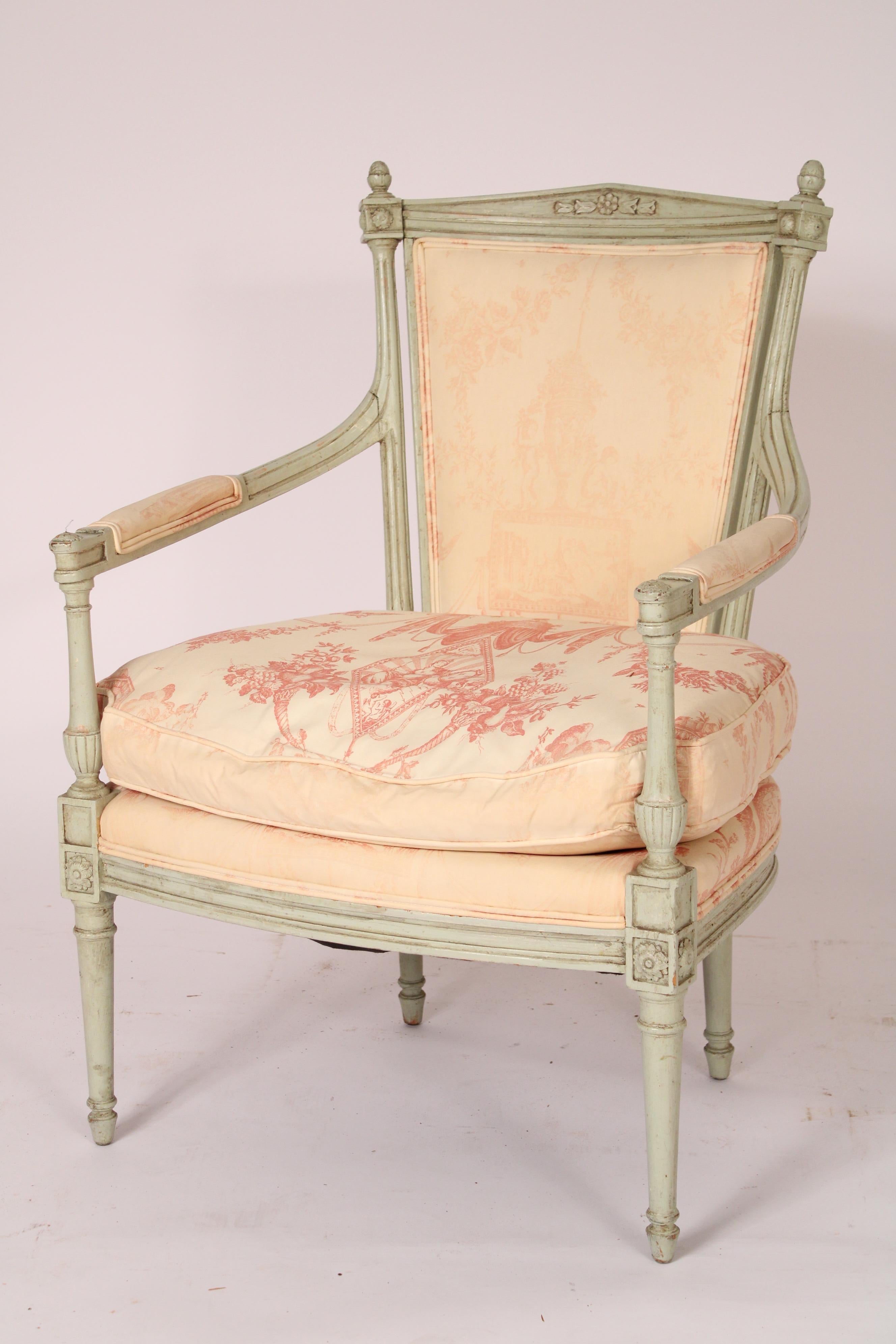 Paire de fauteuils anciens peints de style Directoire, vers 1900. Les accoudoirs sont de forme triangulaire et flanqués de fleurons en forme de glands. Les supports d'accoudoirs sont en forme de vase allongé et les pieds sont tournés et fuselés.