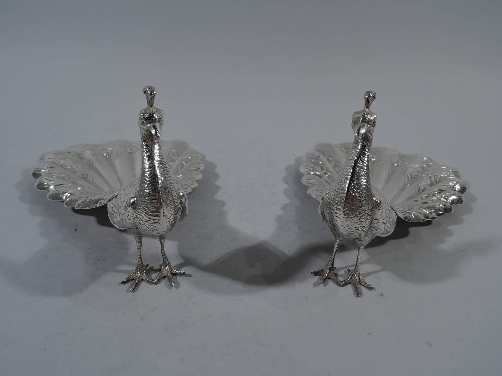 Pair of sterling silver peacocks. Made by Durgin (part of Gorham) in Providence, circa 1920. Each: Upright body, erect head, and downed tail. Realistic feathers, talons, crown, and beak. Tail hollowed - perfect for holding treats. Hallmark includes