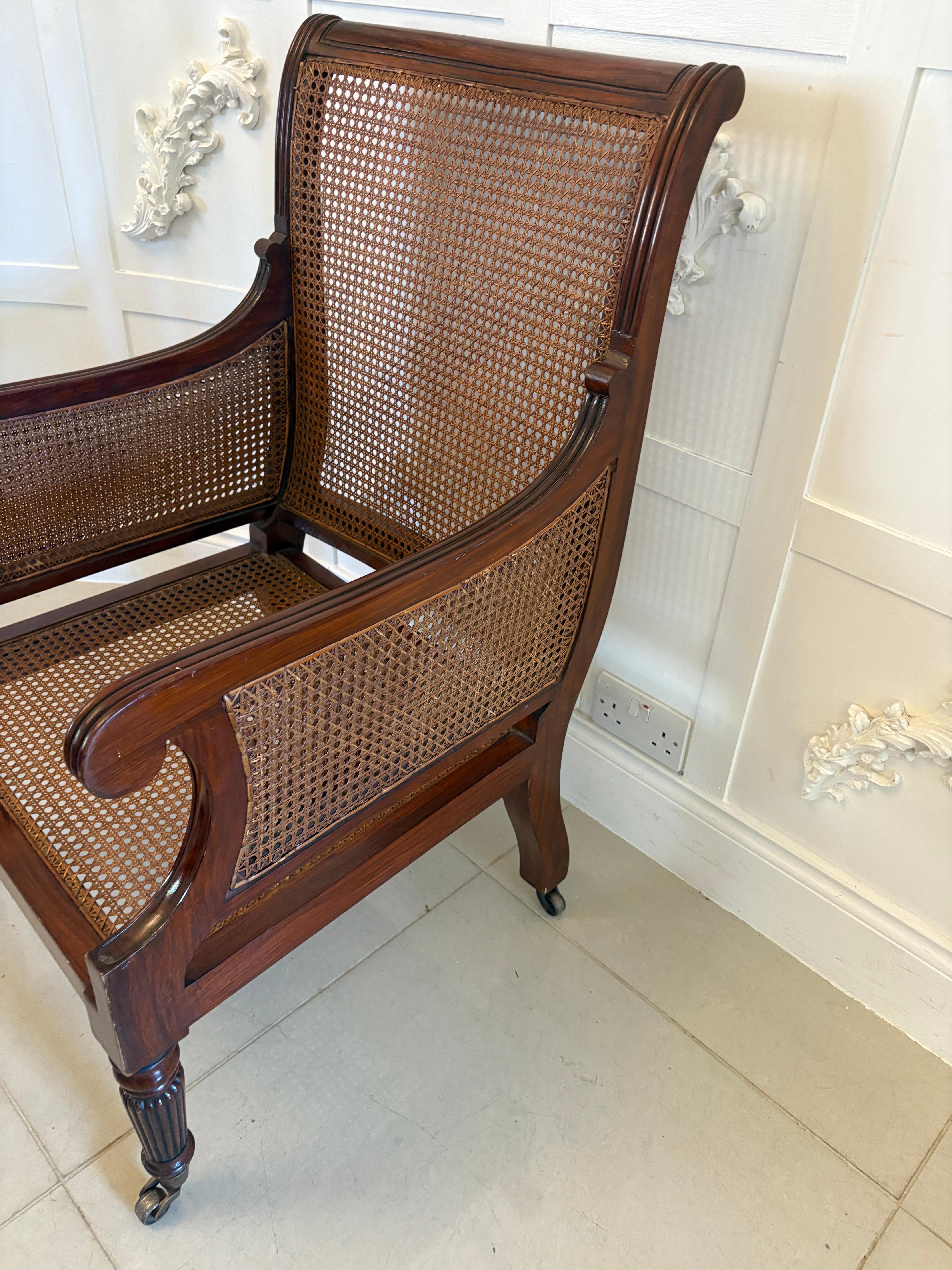 Paire de fauteuils de bibliothèque Bergère en acajou de qualité édouardienne, avec dossier et accoudoirs cannelés en acajou, reposant sur d'élégants pieds cannelés tournés et effilés à l'avant et sur des pieds arrière en forme de balayage, roulettes