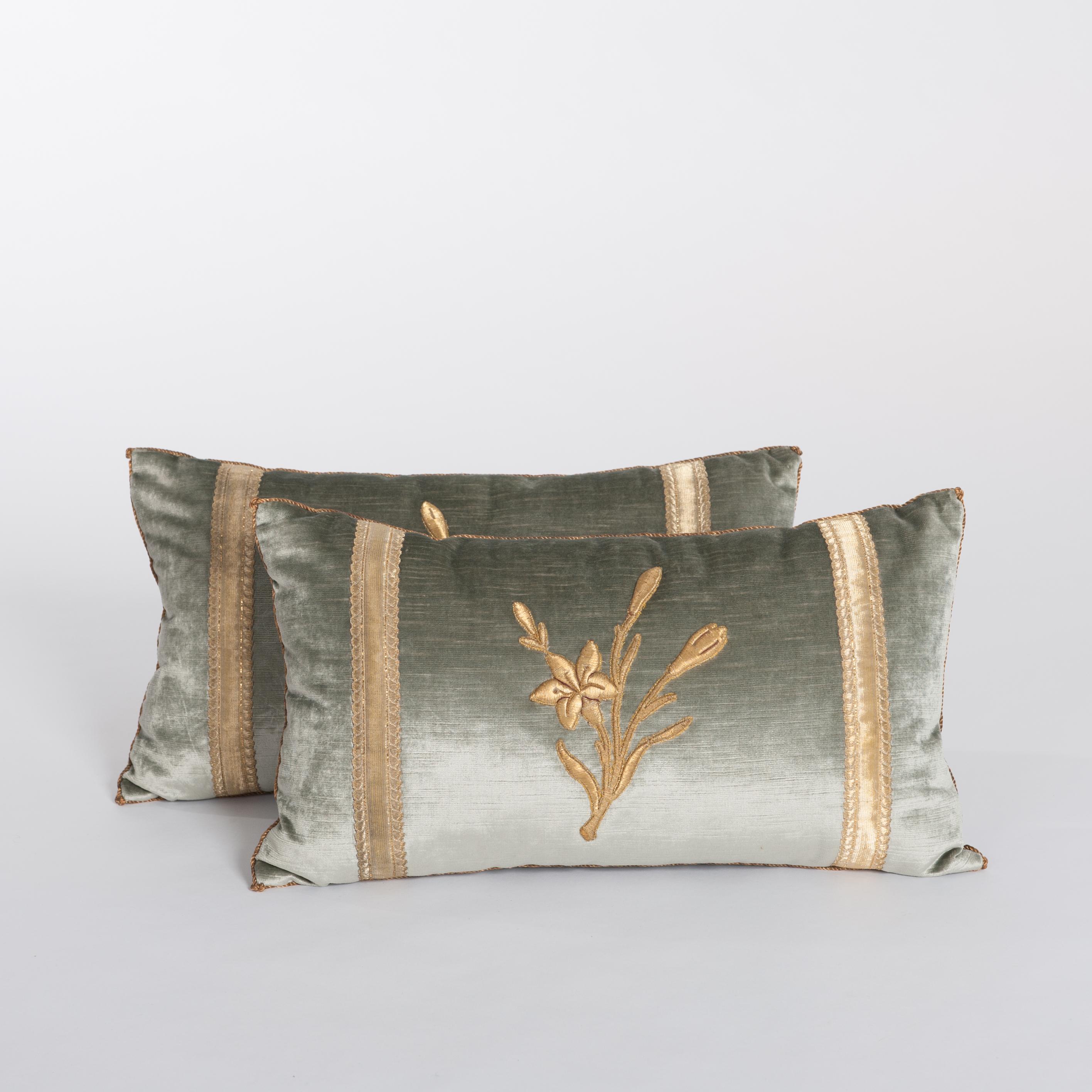 A pair of down-filled pillows fabricated with a 19th century raised gold metallic
embroidery of flowers with antique gold metallic gallon on pale French green-grey velvet.
Hand trimmed with vintage gold metallic cording knotted in the corner.