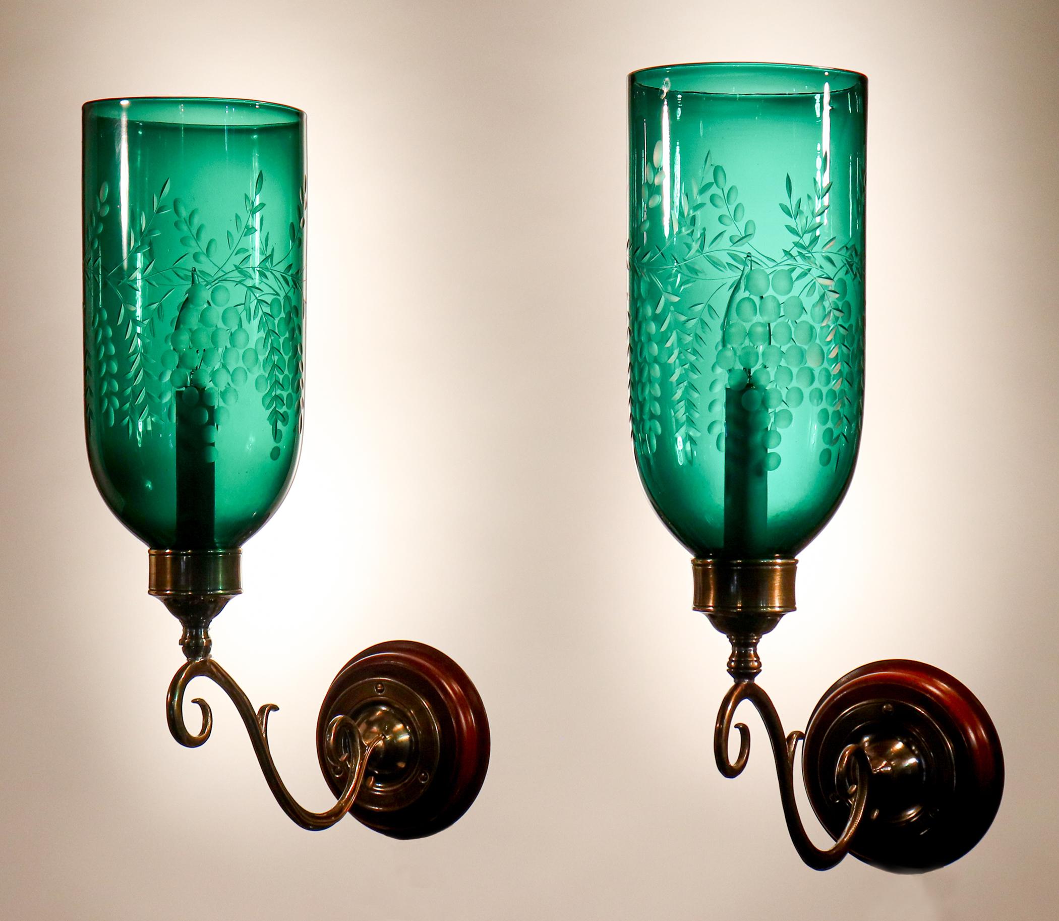 An exceptional pair of English hurricane shade sconces, circa 1890, with a deep green hue. These authentic hand blown glass shades have lovely straight form and are etched with a Classic grape motif. The wall sconces are newly electrified, with each