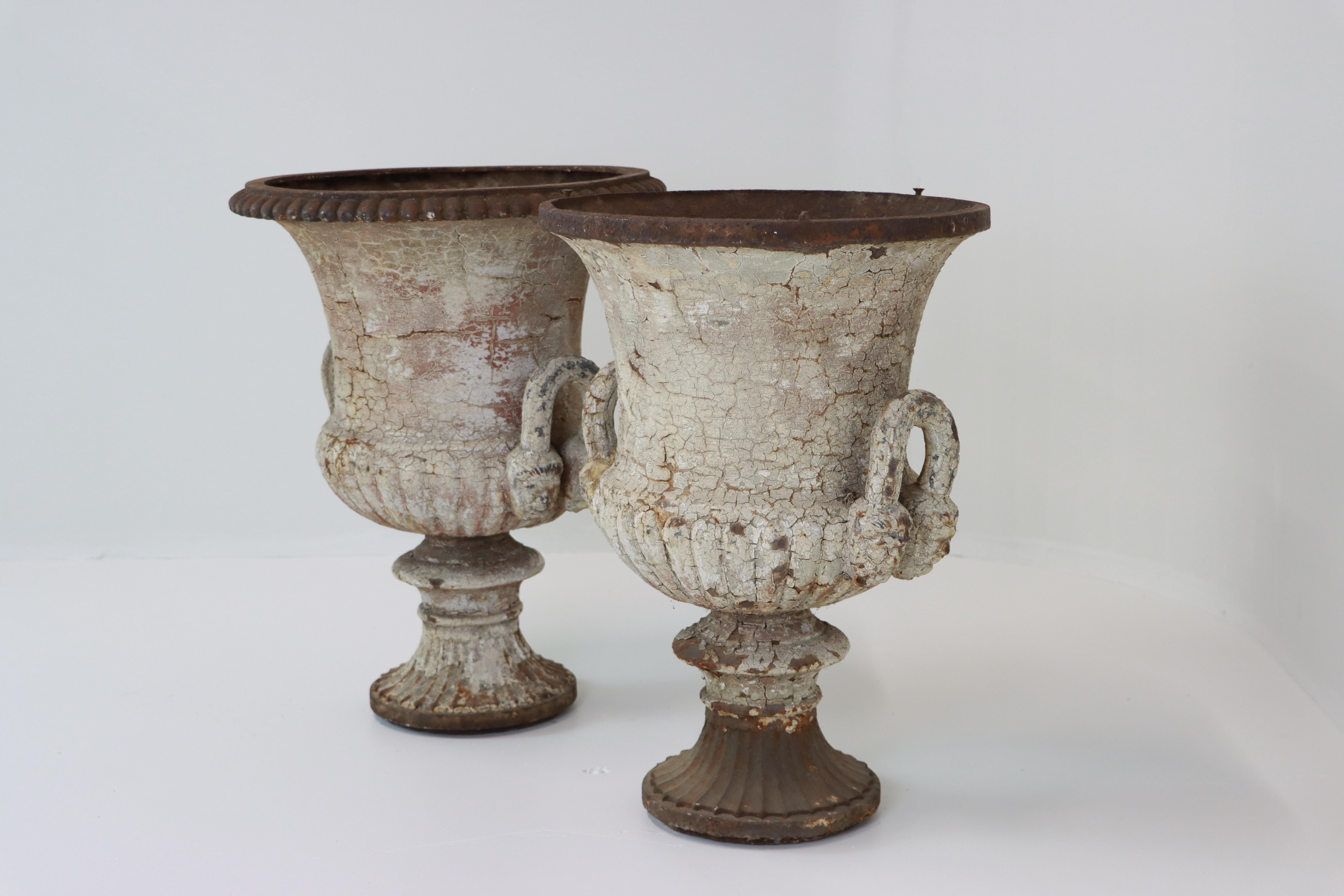 A lovely pair of antique English country house cast iron garden urns in the classical campana form and attributed to the renowned Derby foundry of Andrew Handyside & Co. Each urn features a flared rim (one urn is missing the top egg and dart band),