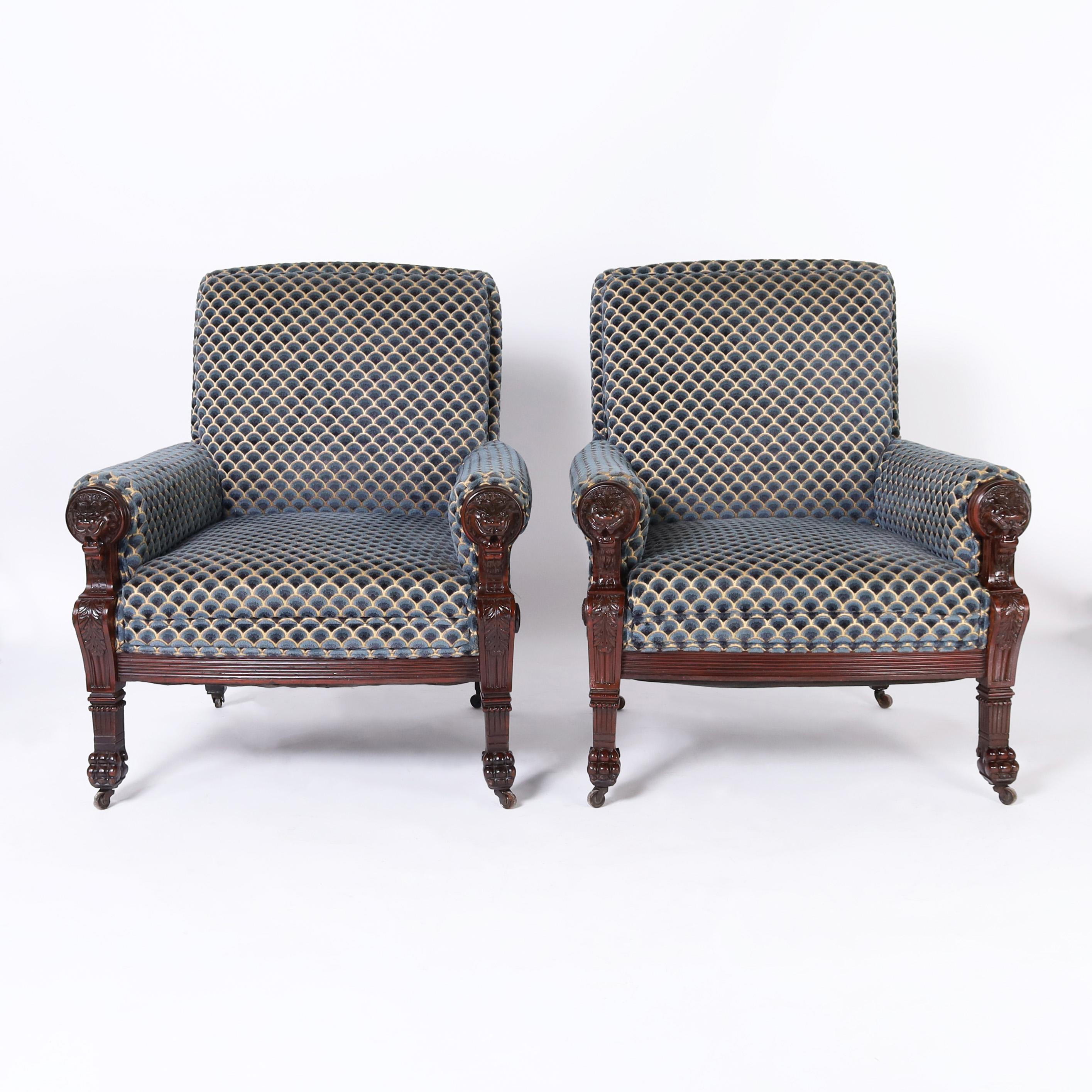 Impressive pair of 19th century English Victorian armchairs built for comfort and crafted in mahogany with carved lion heads acanthus leaves and paw feet on casters.