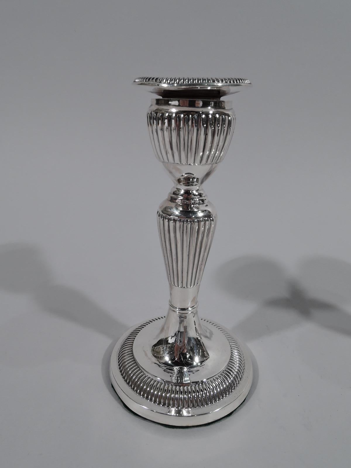 Pair of Victorian Georgian sterling silver candlesticks. Made by Hilliard & Thomason in Birmingham in 1894. Each: Urn socket with detachable bobeche on tapering shaft on raised foot. Dense and linear gadrooning. Interlaced script monogram engraved