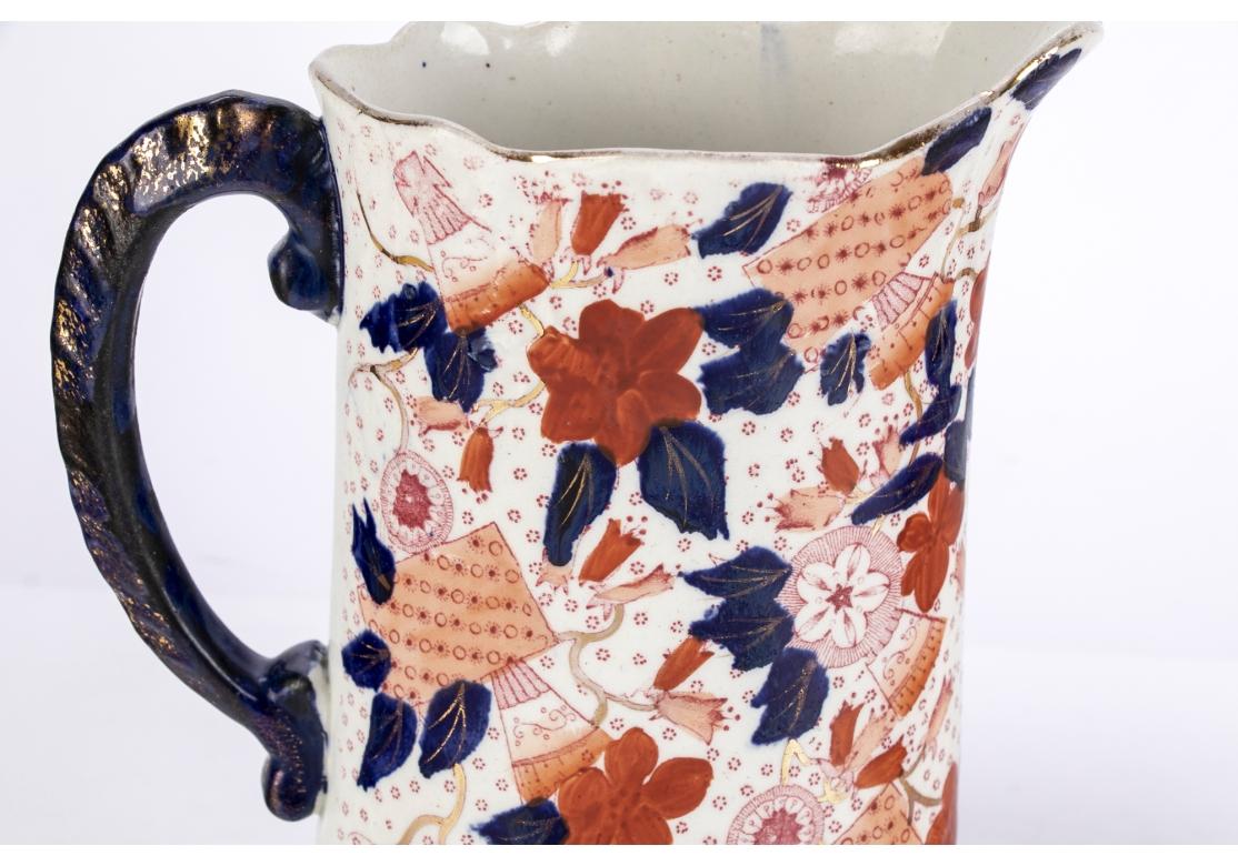 Pareja de jarras inglesas de cerámica con motivos Imari de ironstone 
con decoración floral esmaltada en azul y rojo hierro, bordes festoneados y decoración parcelaria dorada.
Patrón 1440 marcado a mano en el verso.

Dimensiones: 7