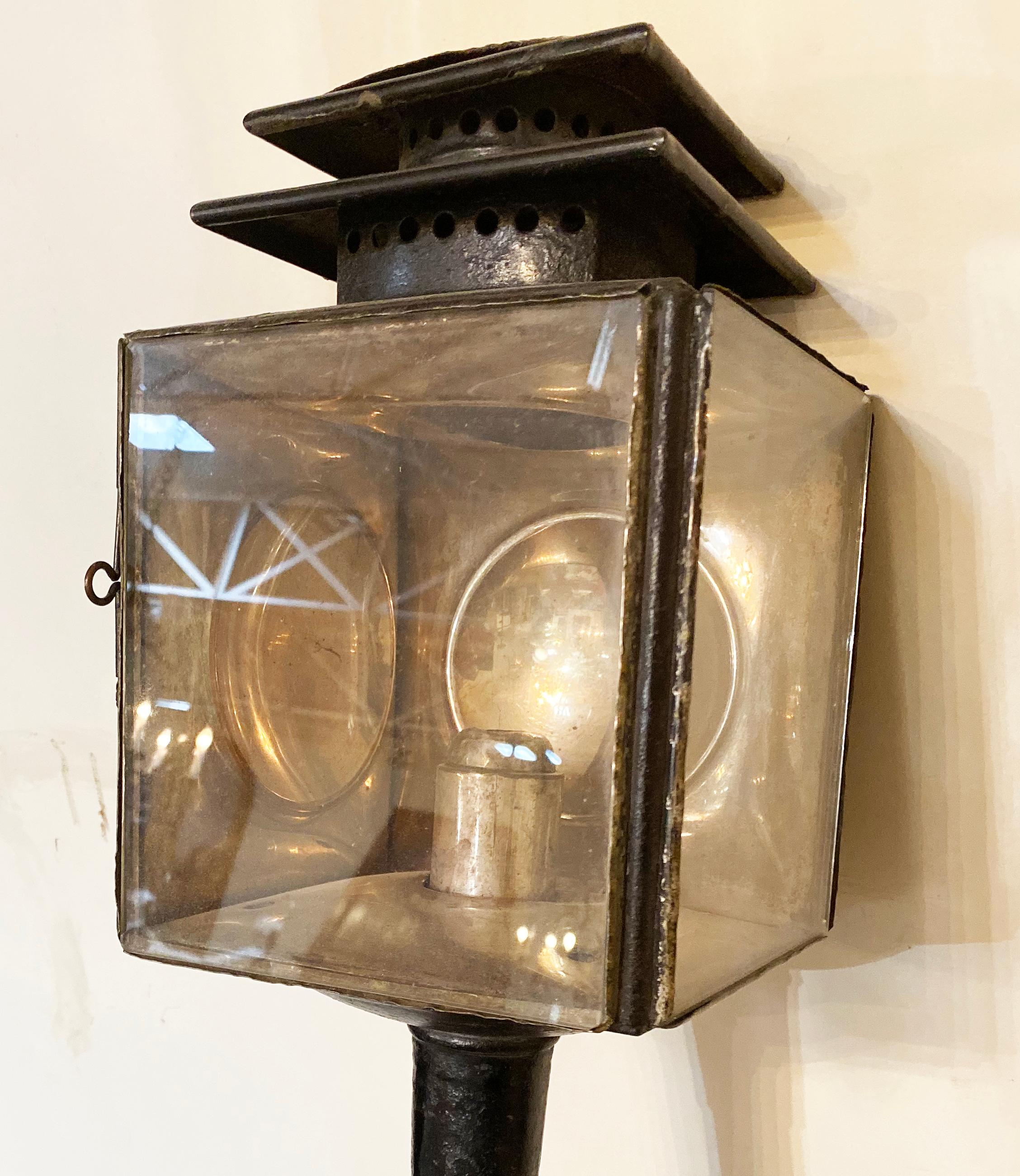 This pair of metal carriage lanterns originate from England, circa 1800s. 

Measurements: 21'' H x 6.5'' D x 7.5'' W.