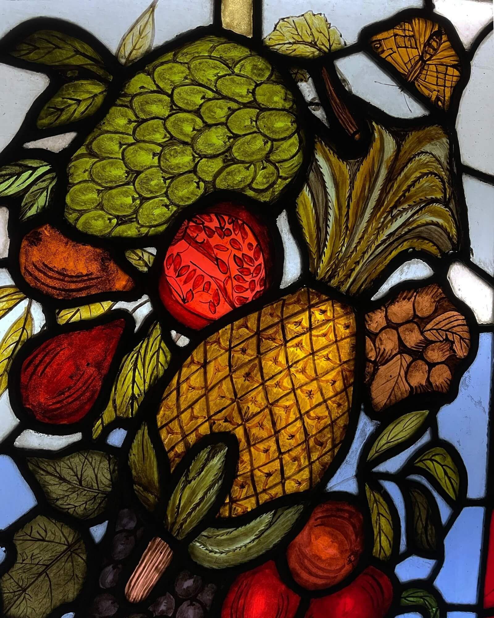 A beautiful pair of late 19th century antique English stained glass windows depicting an abundance of colourful fruits including pineapples, pomegranates, grapes and cherries alongside butterflies.

With slight variances in the design, these