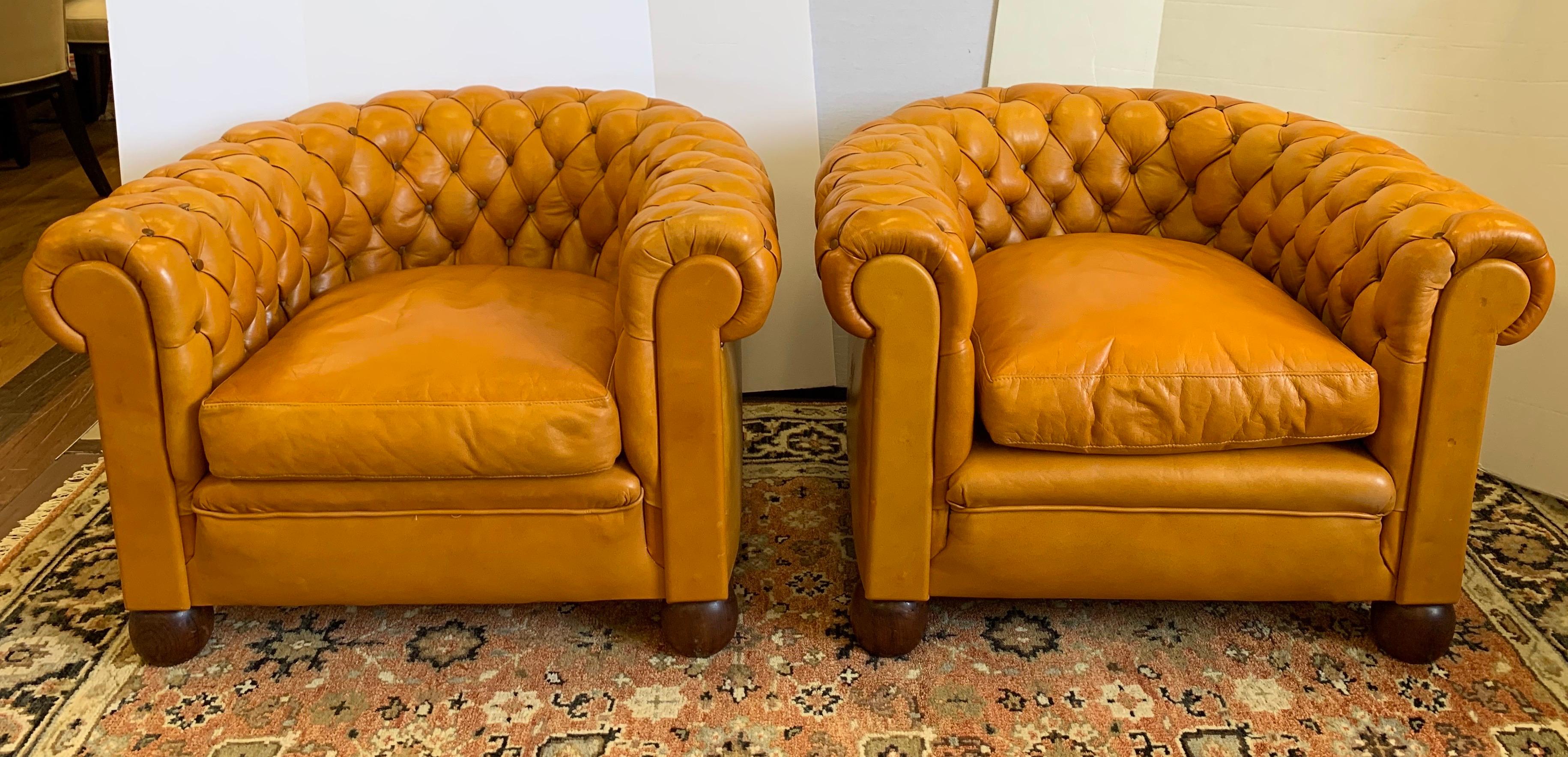 Stunning pair of English leather chesterfield club chairs. Feature distinctive, rolled arms and deep buttoned tufted detailing and is upholstered in the softest top-grain, butterscotch colored leather accented with brown button tufting. There are